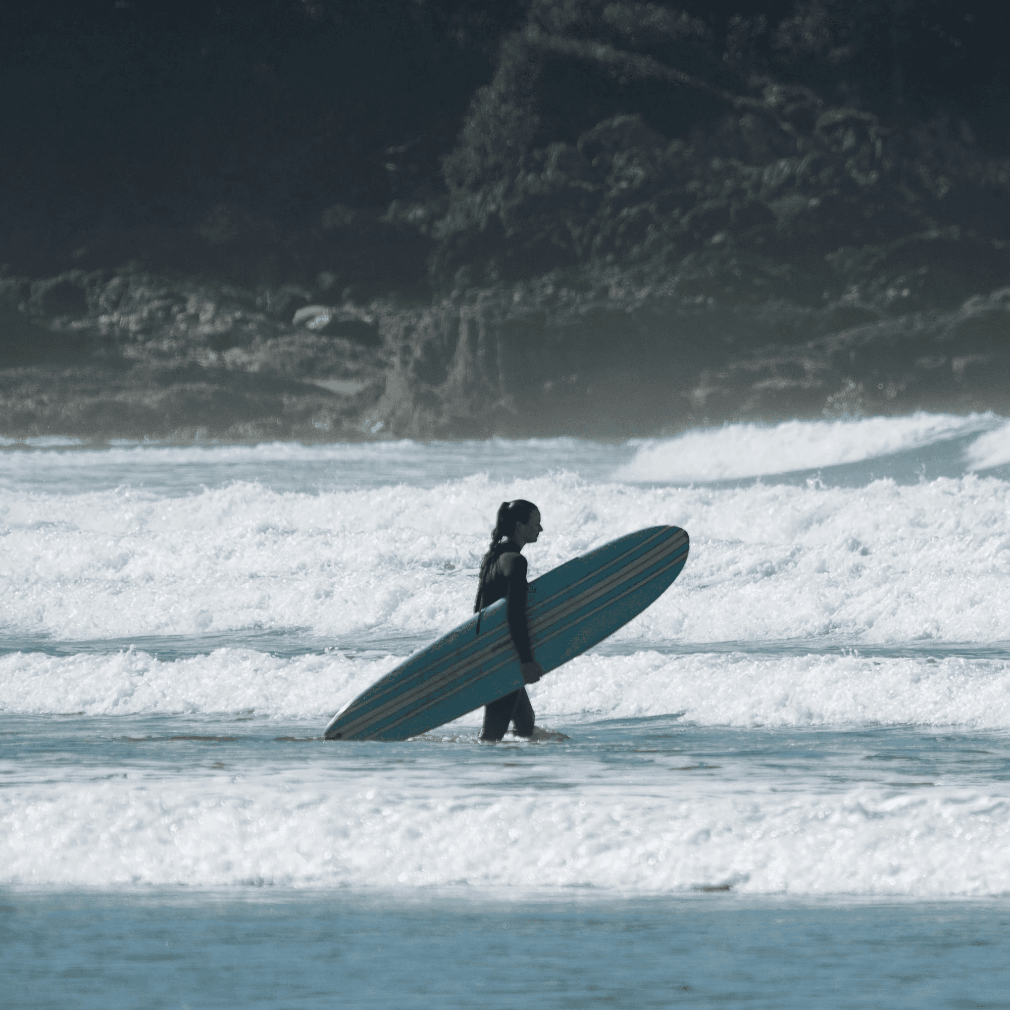 a person walking in the water with a surfboard