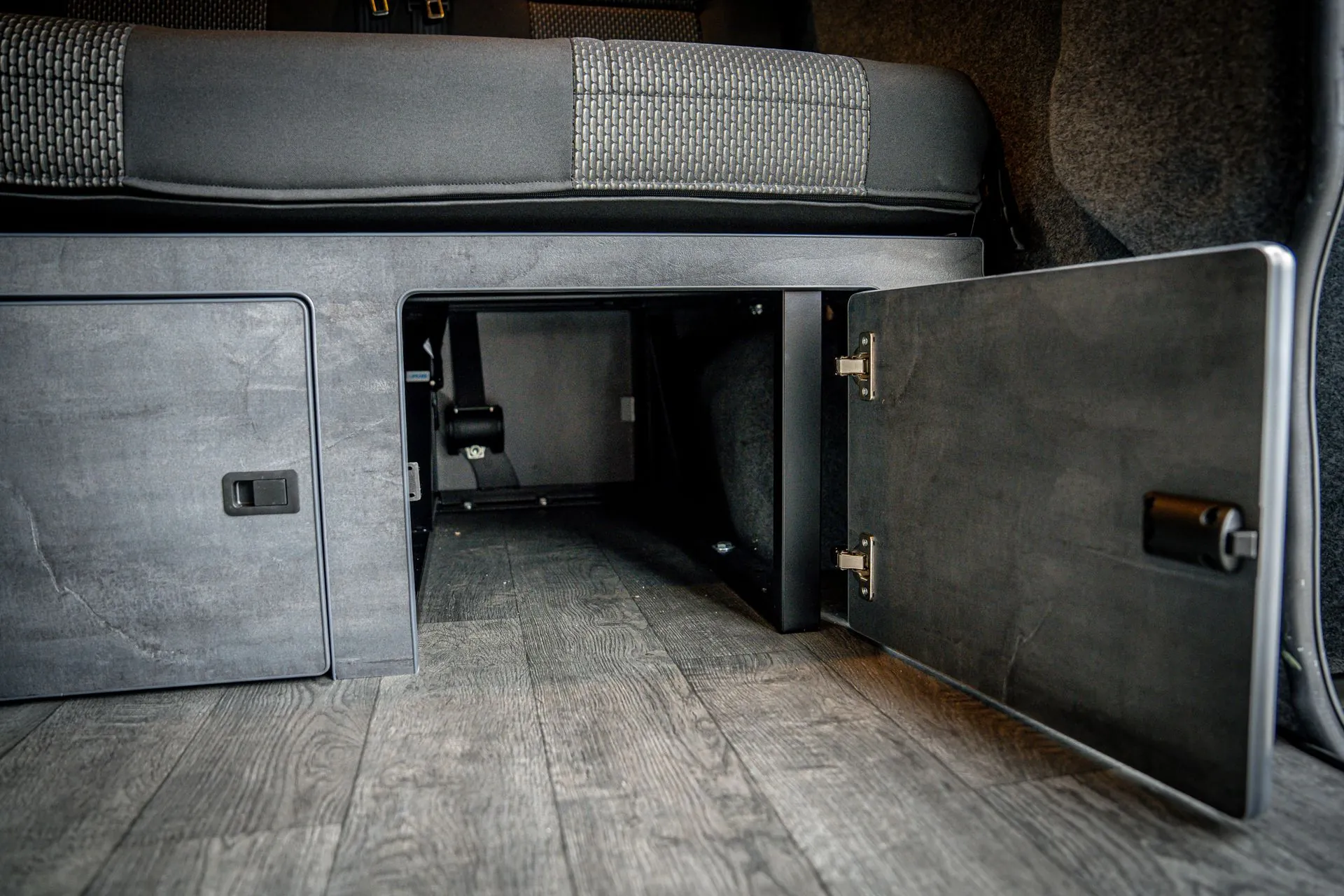 Open under-seat storage cupboard beneath the Renault Trafic RIB bed, with Jacobean Oak flooring