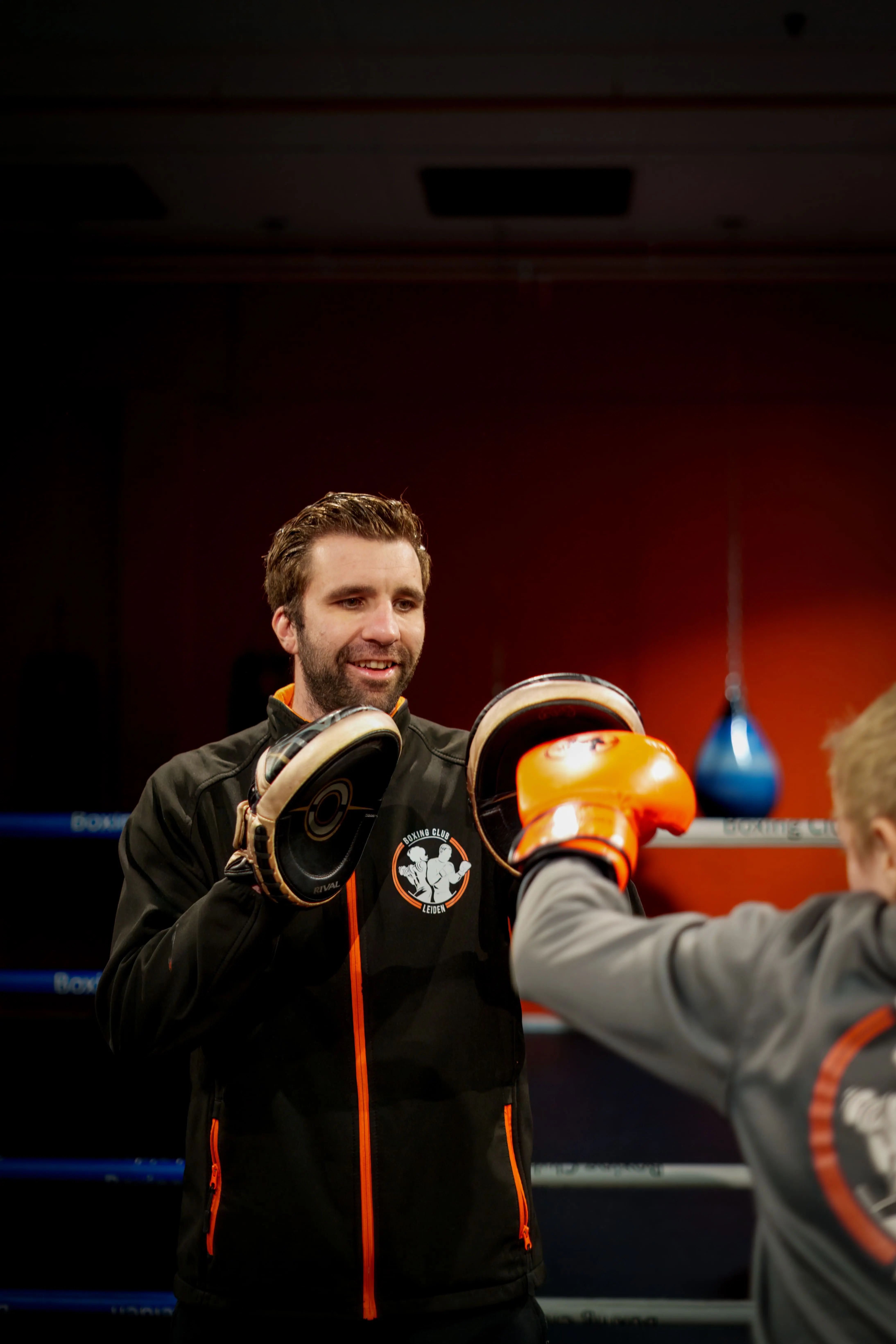 Lachende trainer vangt een stoot op de handpad op