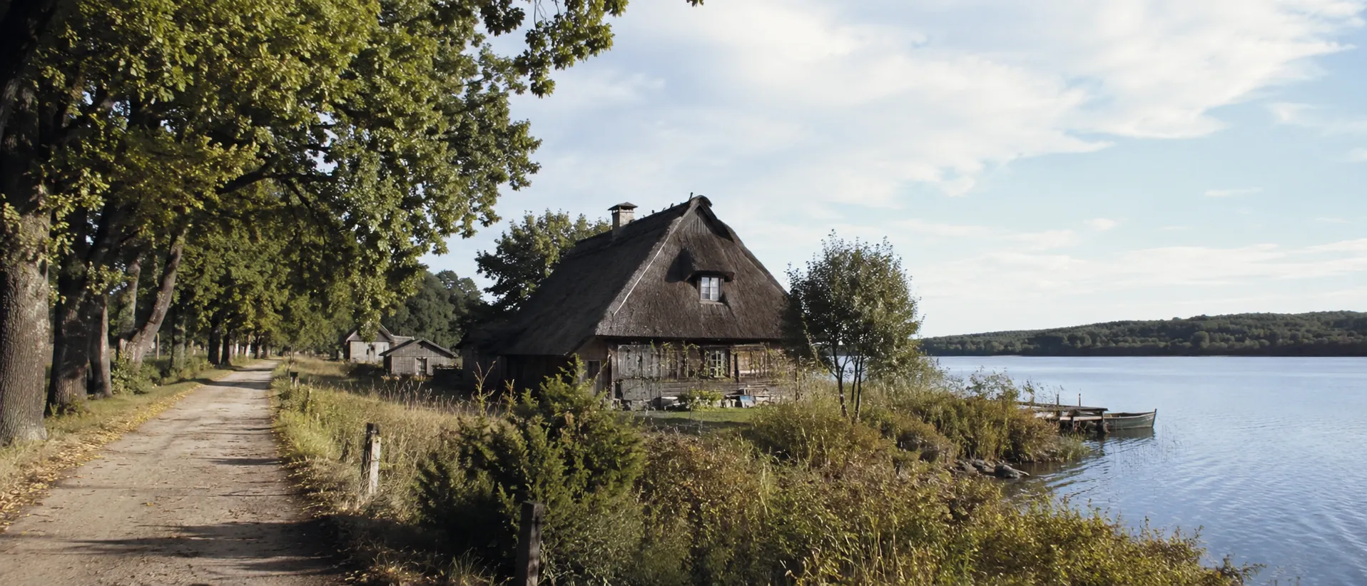 Brandenburgischer See mit reetgedecktem Fischerhaus, Uferweg und alten Bäumen