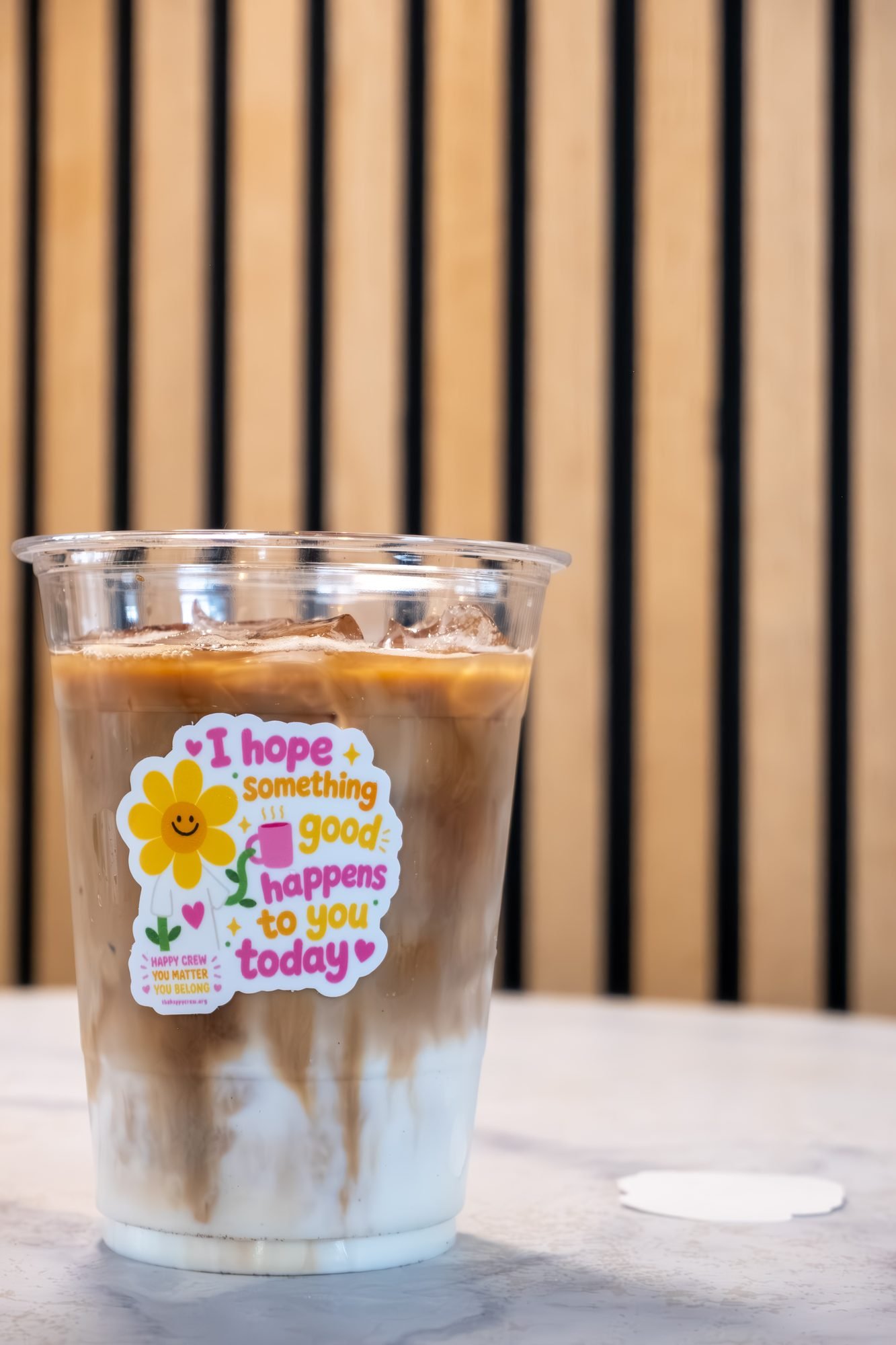 An iced latte in a cup with a sticker that says I hope something good happens to you today