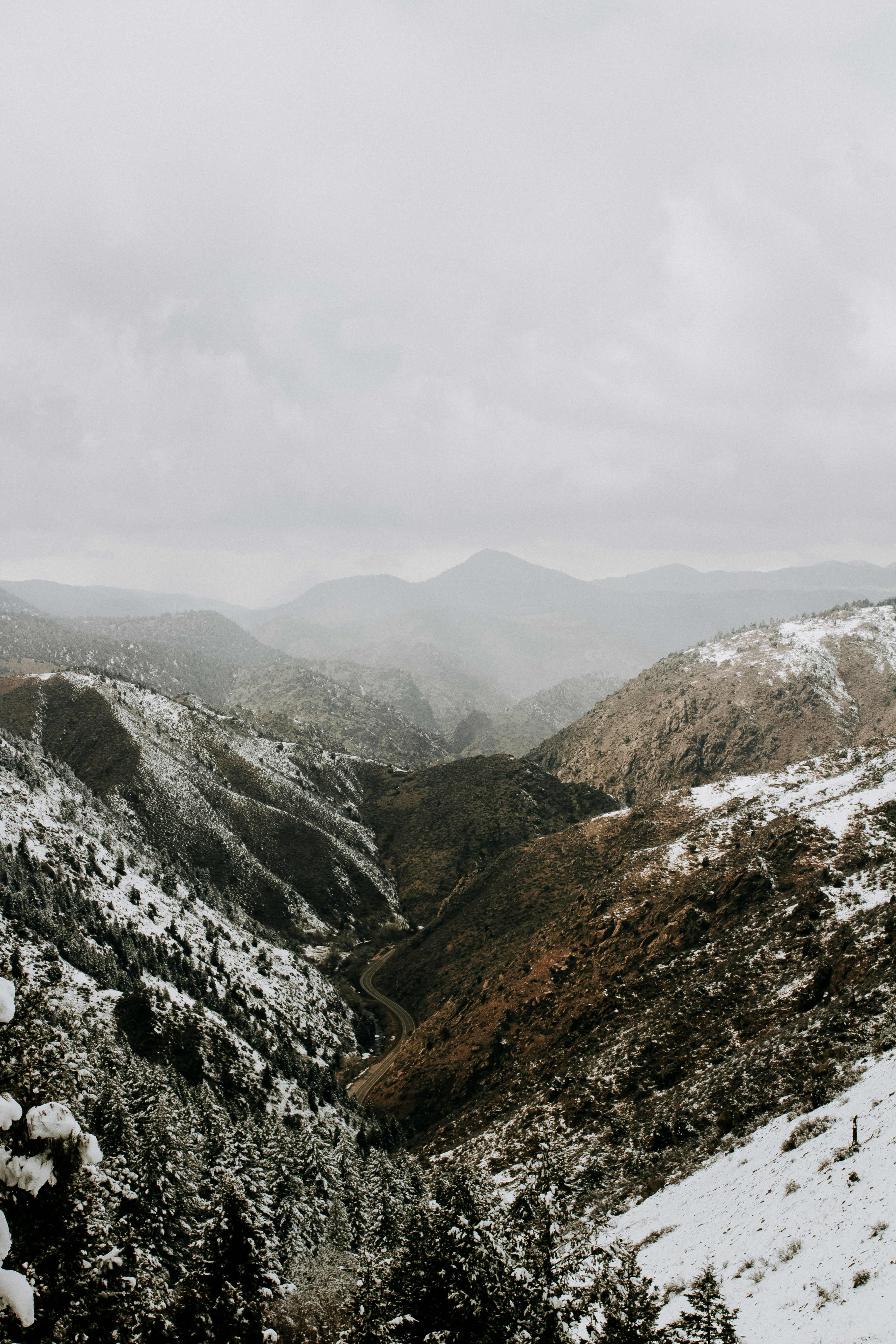 A wide angle of moutains dusted with snow and covered in grey fog.