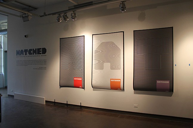 A set of black and white printed posters that show a letter and a colorful square near a corner with text Hatched.