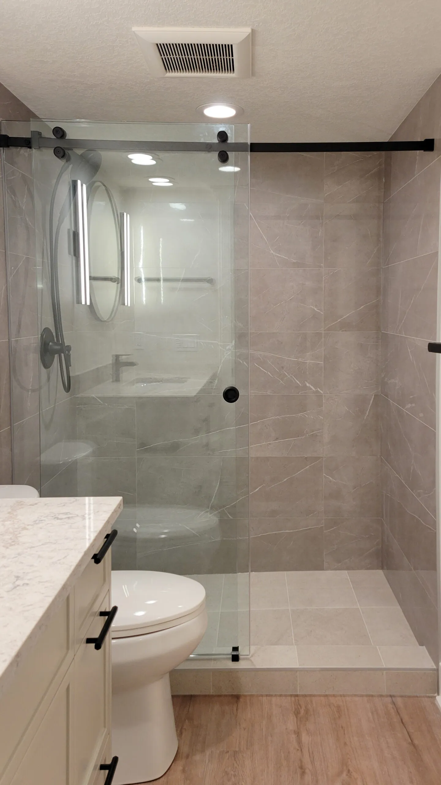 Image of walk in shower with large format warm grey tiles.