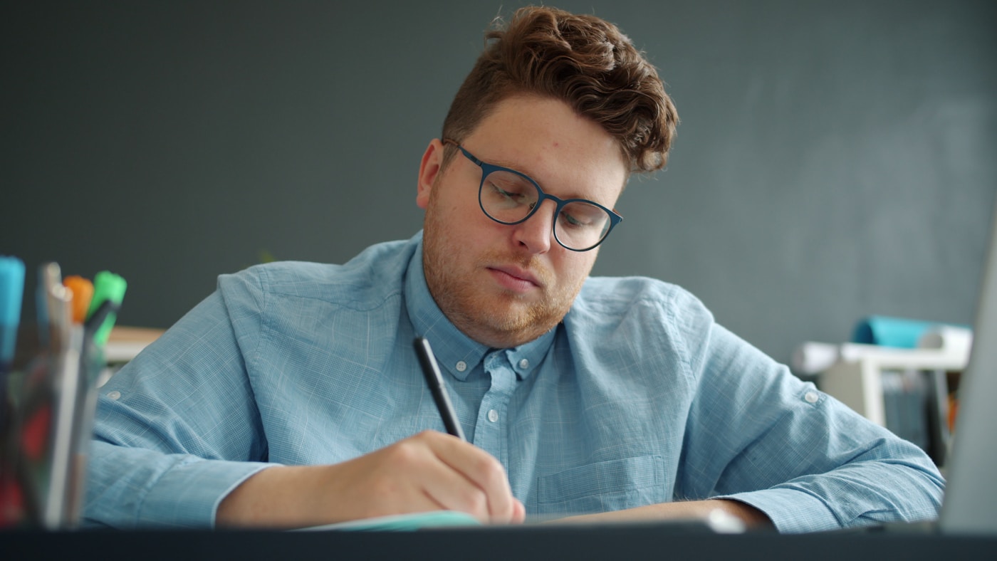 A student drafting notes by hand before checking the work with an AI assistant