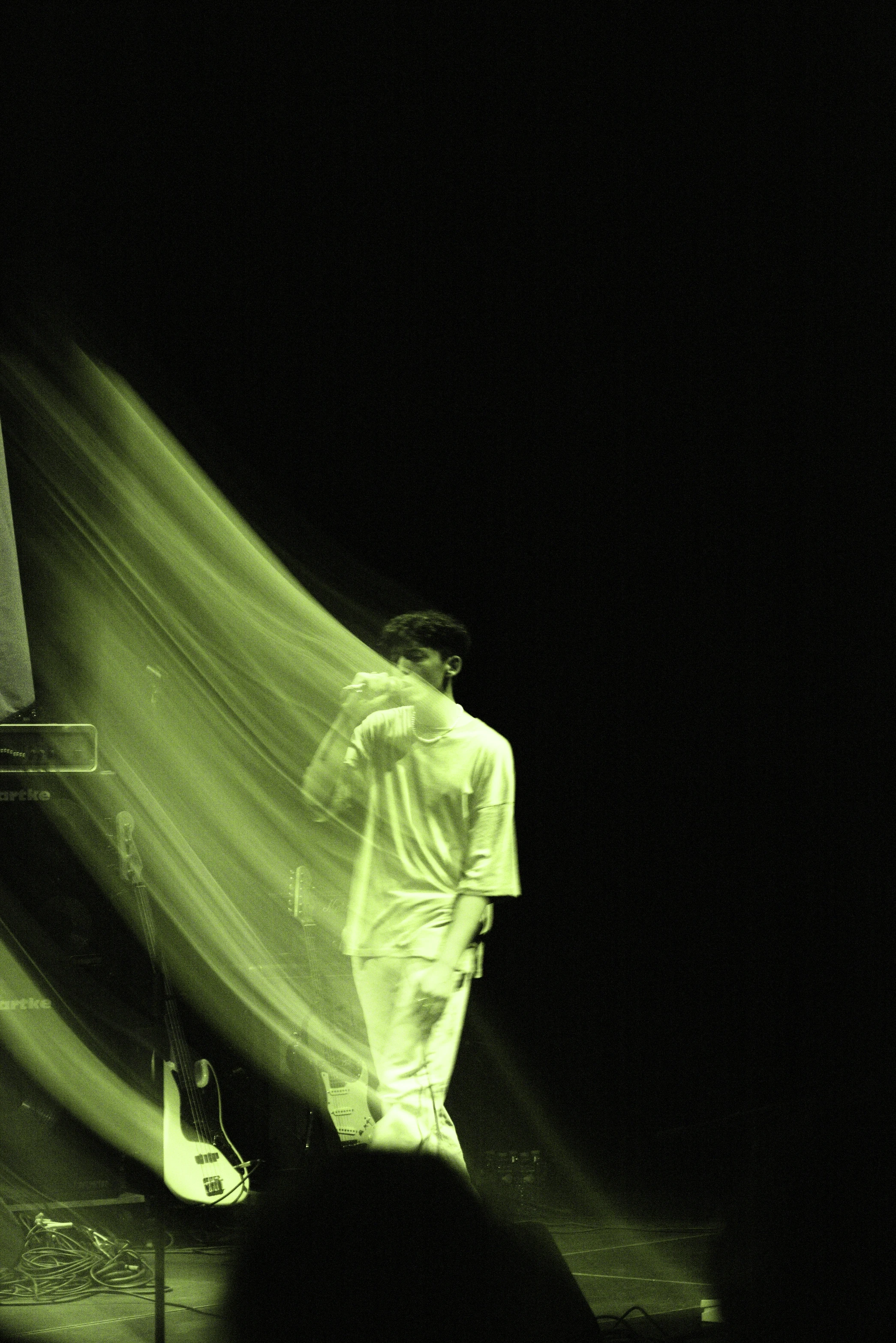 A performer illuminated in green light, partially obscured, creating a dramatic and mysterious atmosphere.