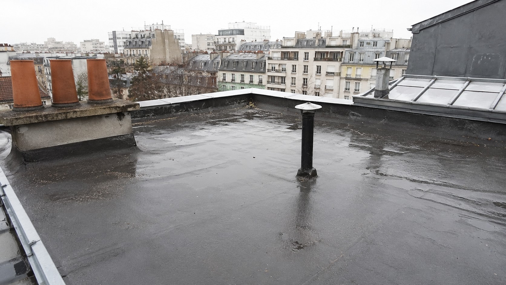 Vue d’une toiture-terrasse d’immeuble à Paris lors d’une opération d’entretien préventif. La surface étanchée en membrane bitumineuse est inspectée pour vérifier l’état général, les évacuations d’eaux pluviales, les sorties de ventilation, les lanterneaux et les points sensibles d’étanchéité.