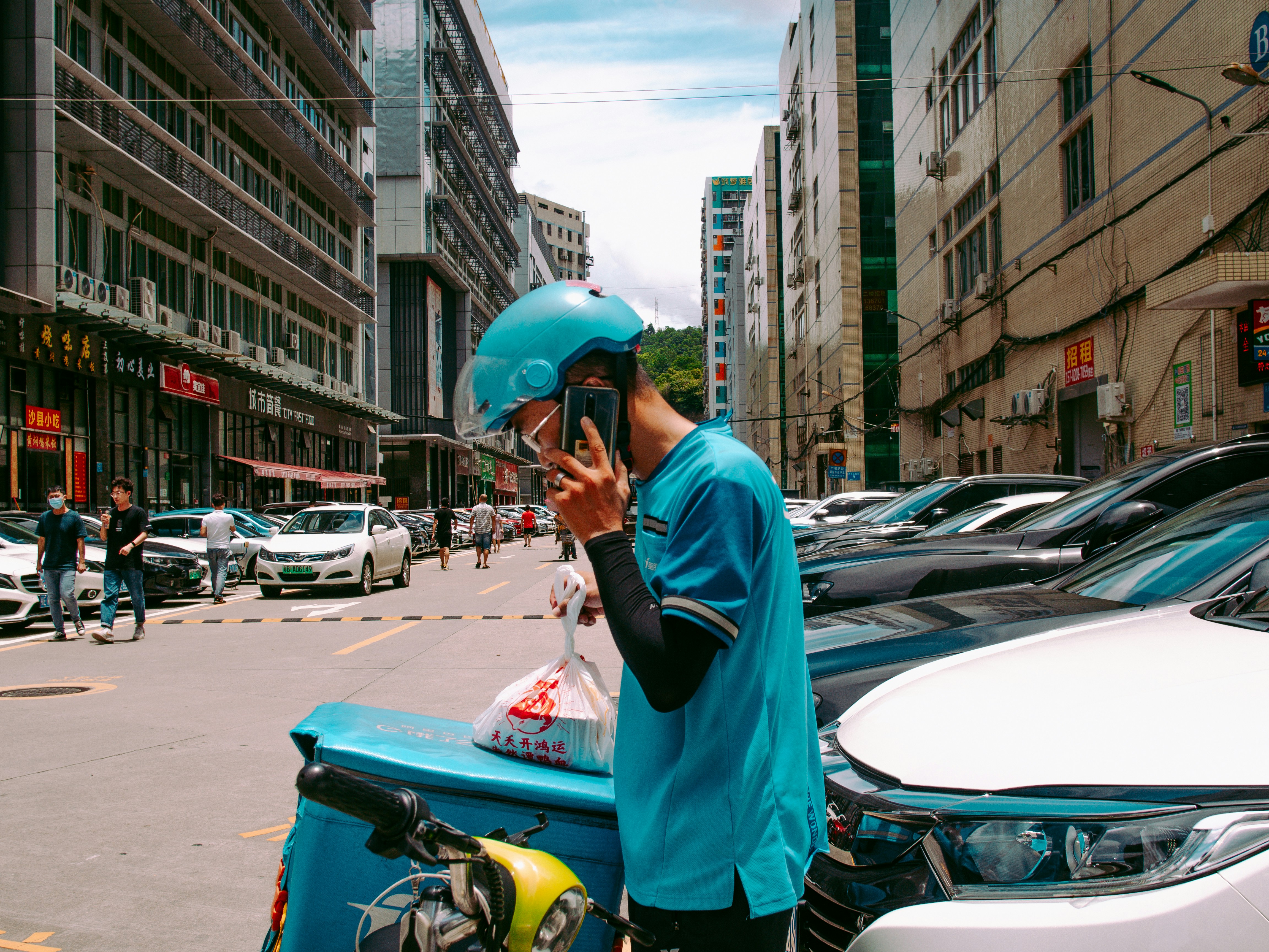 man in blue helmet and blue jacket standing beside cars during daytime