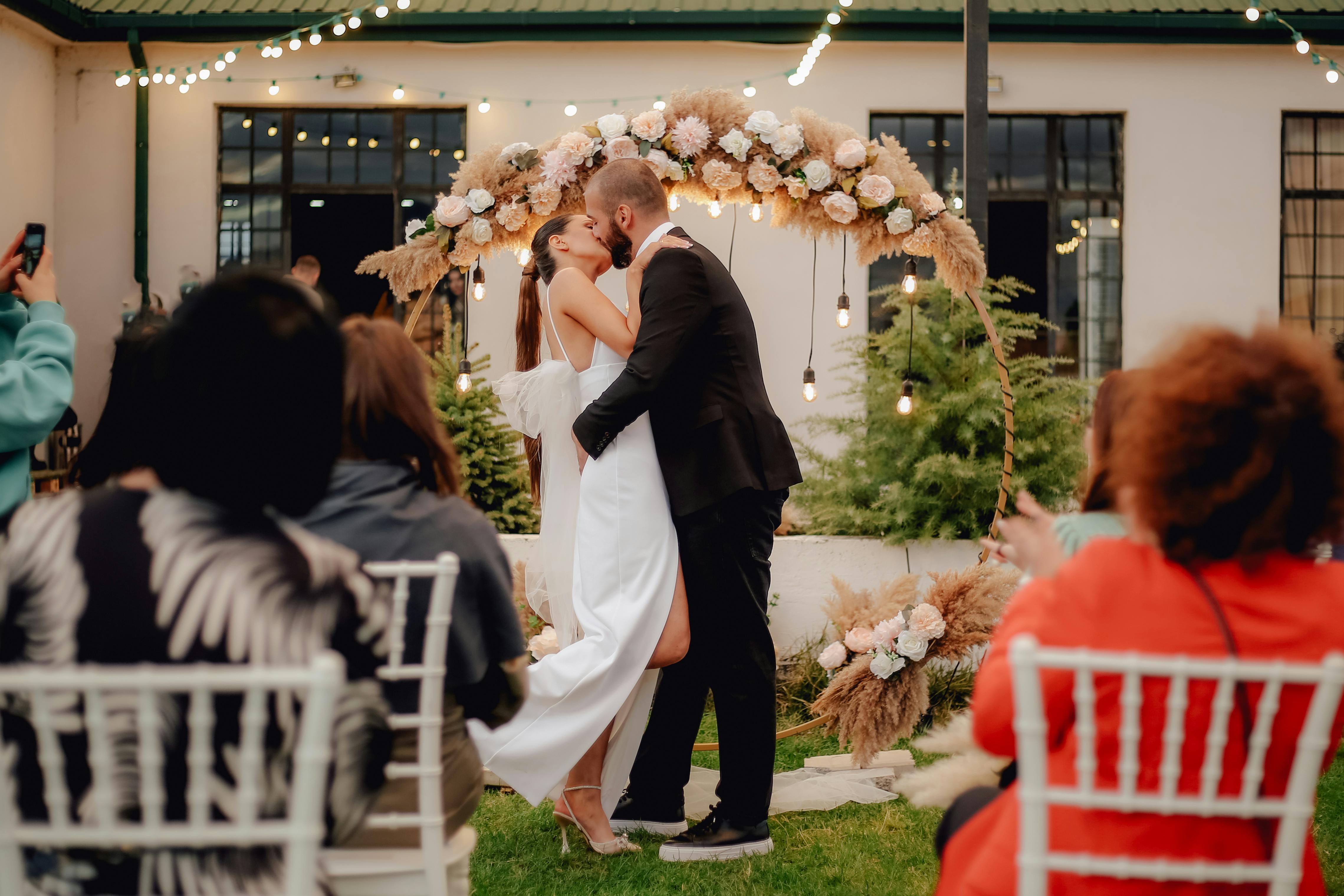 A bride and groom share a kiss surrounded by a joyful bridal party.