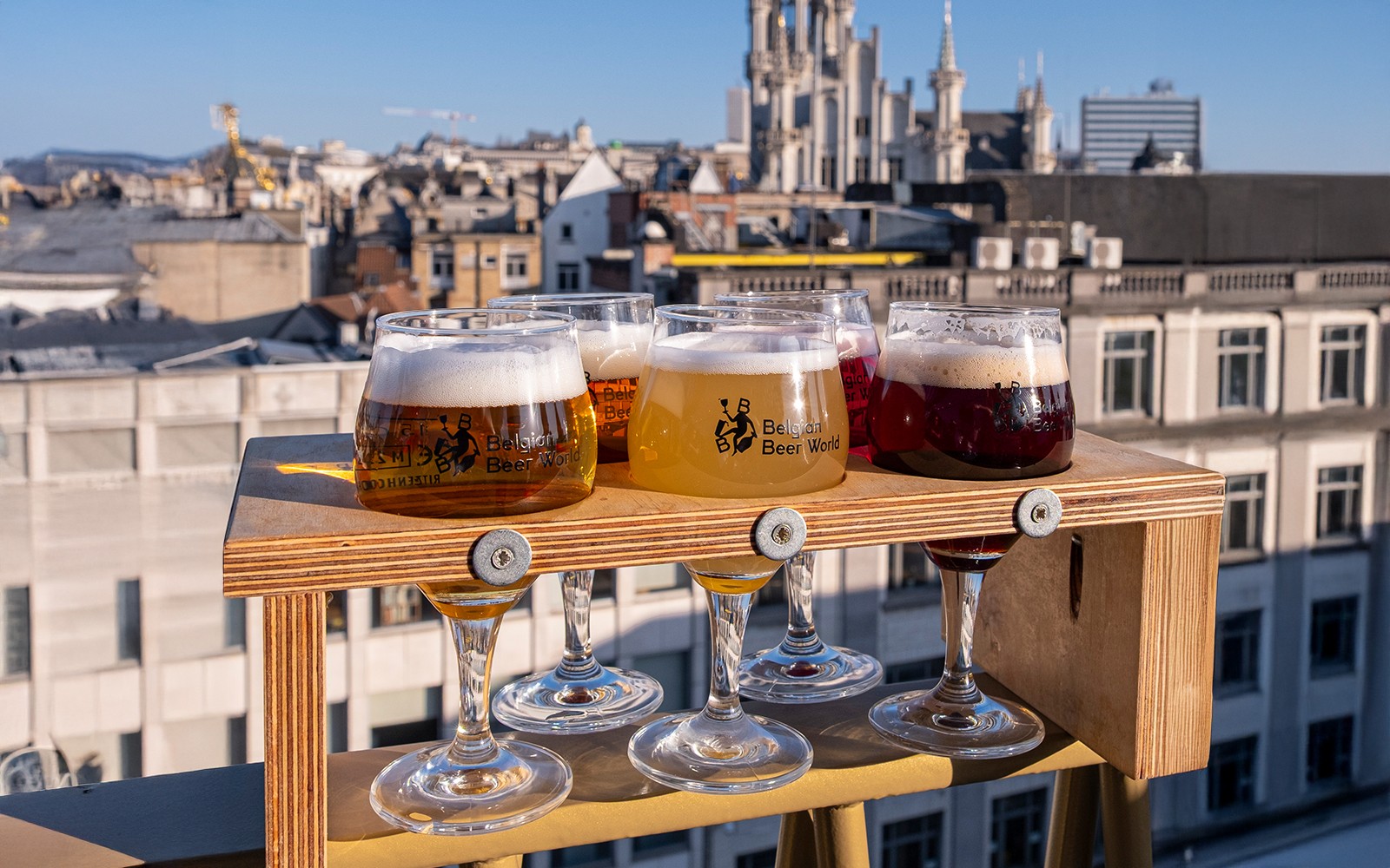 Kóstolás belga söröspoharakból a belga sör világ élmény keretében, Brüsszel városképével a háttérben.