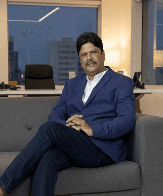 Portrait of a young man in a dark double-breasted suit and black turtleneck. Soft lighting creates a sophisticated, serious tone.