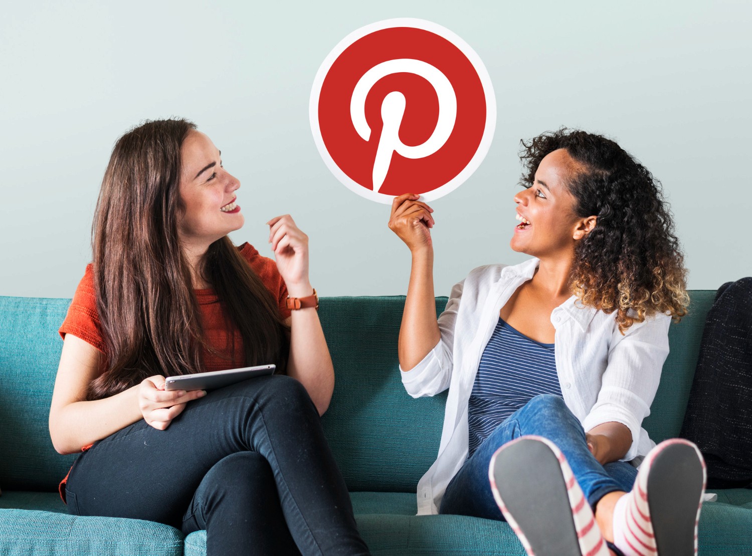 . Two women seated on a couch, engaged in conversation, with a Pinterest icon displayed prominently nearby.