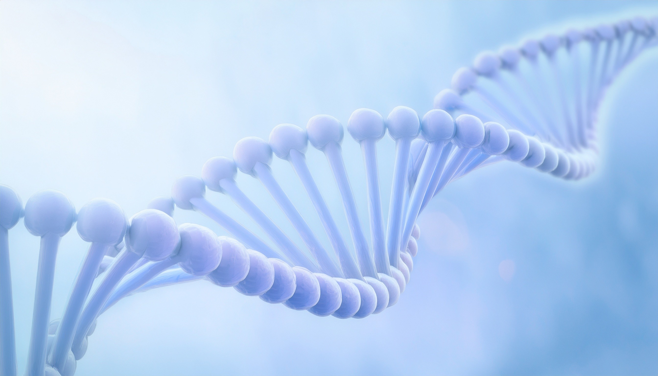 Man wearing an olive green jacket and black shirt, sitting and smiling in front of a light wooden background.