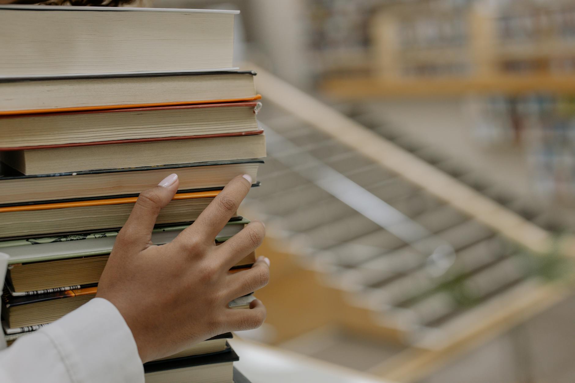 A stack of professional development books and colorful notebooks on a wooden teacher's desk.