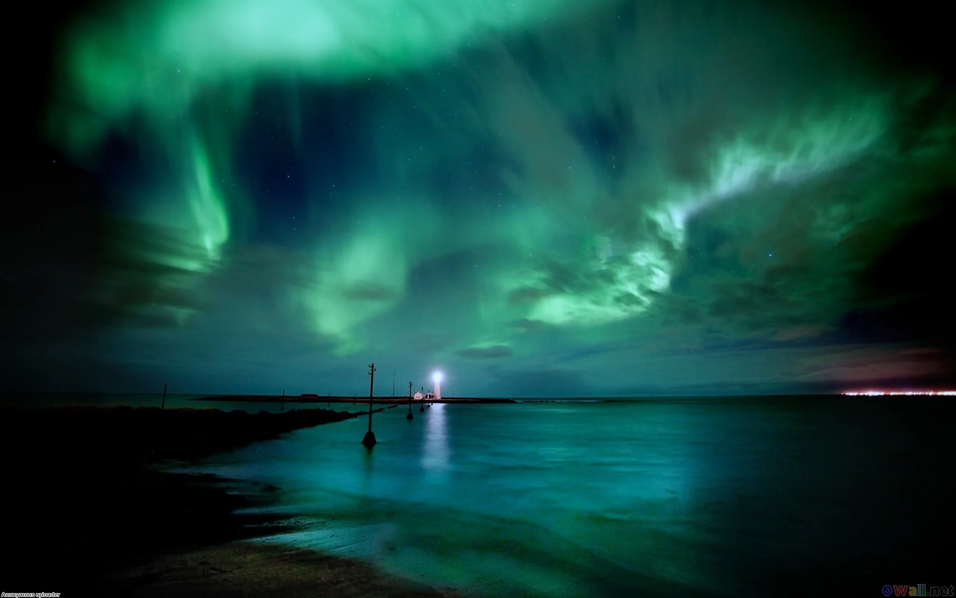 The bright green Northern Lights swirling over Grótta Lighthouse and the dark Atlantic coast in Reykjavík. Photo by Visit Reykjavík.