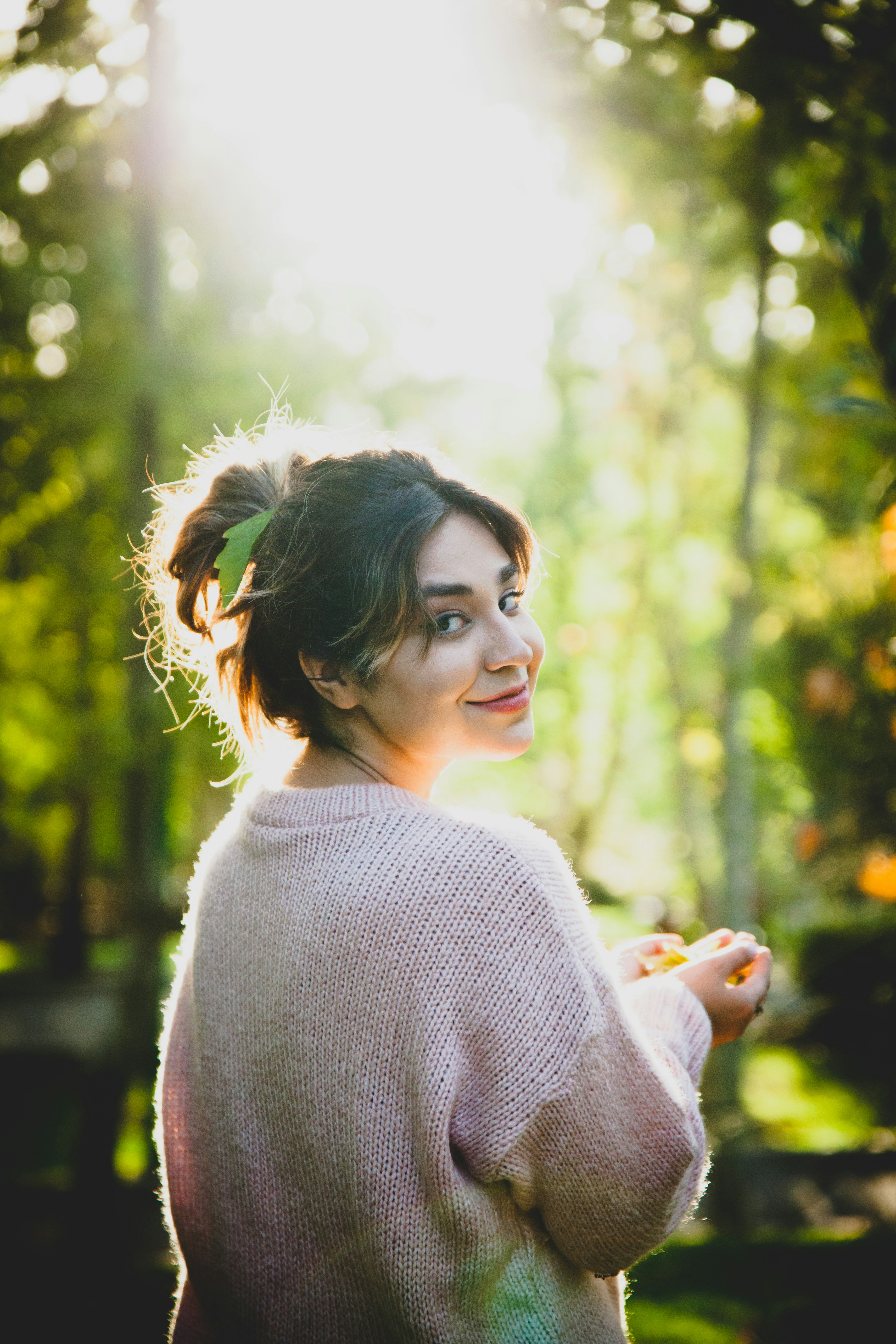 a woman standing in a forest with trees in the background