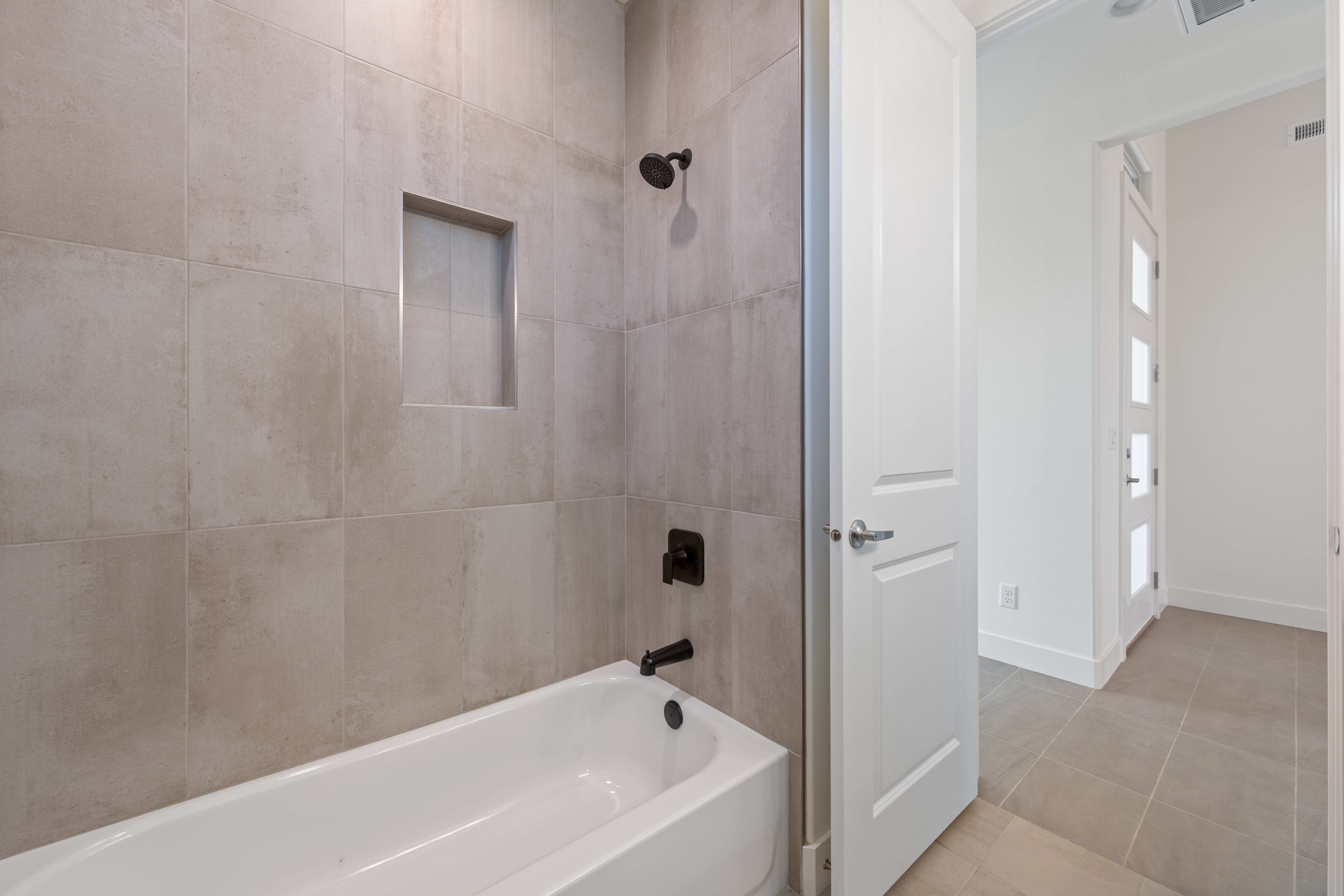 Bathroom in The Nest at Falcon Ridge with a tub and tiled walls, creating a clean and modern look in Hurricane, Utah.