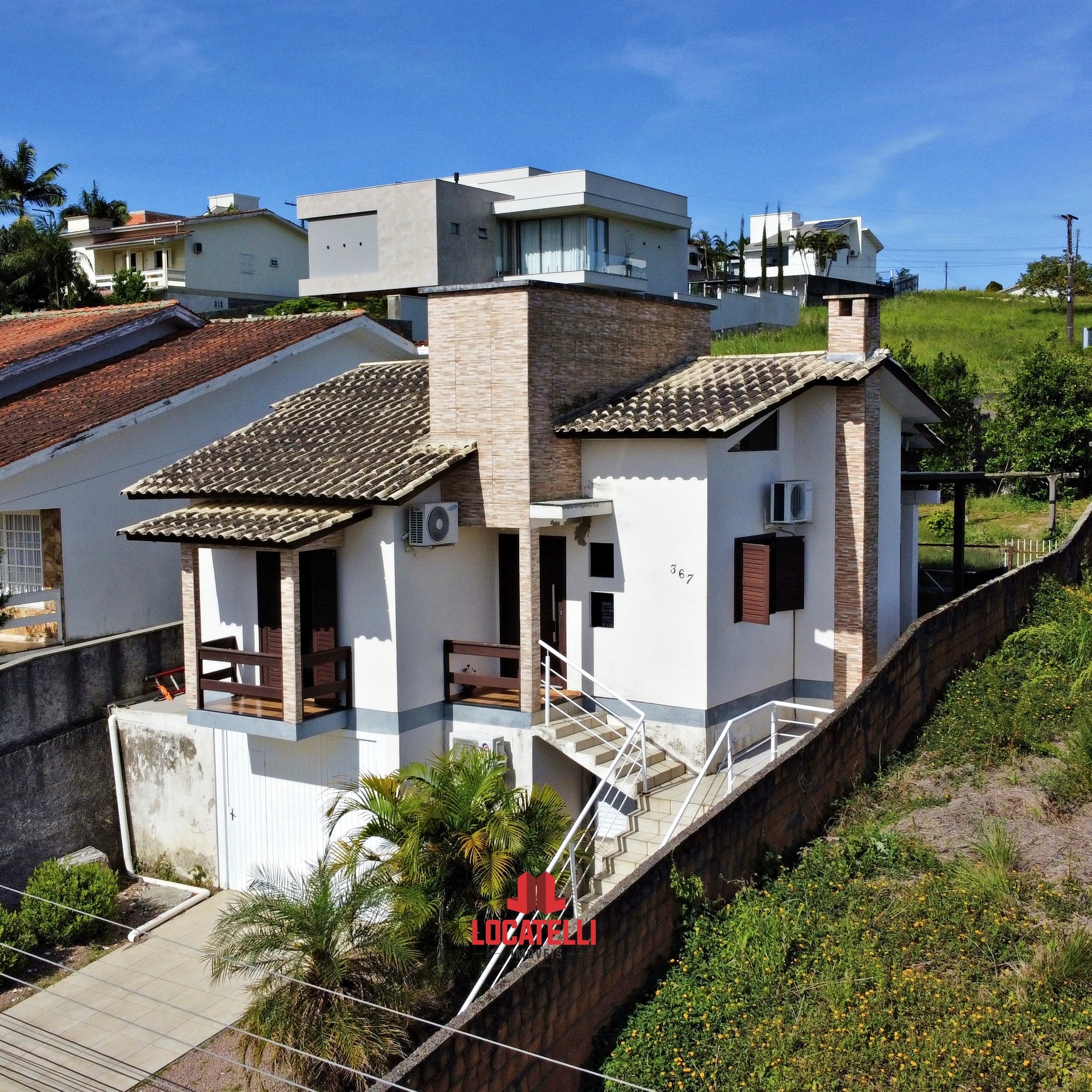 A modern brick house with a two-car garage, well-manicured lawn, and clear blue sky in the background.