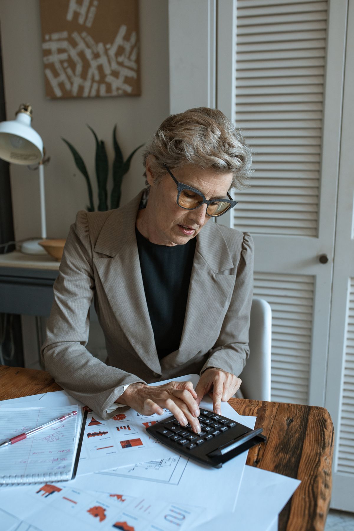 Empreendedora usando calculadora ao lado de relatórios financeiros para analisar o resultado de uma campanha de incentivo.