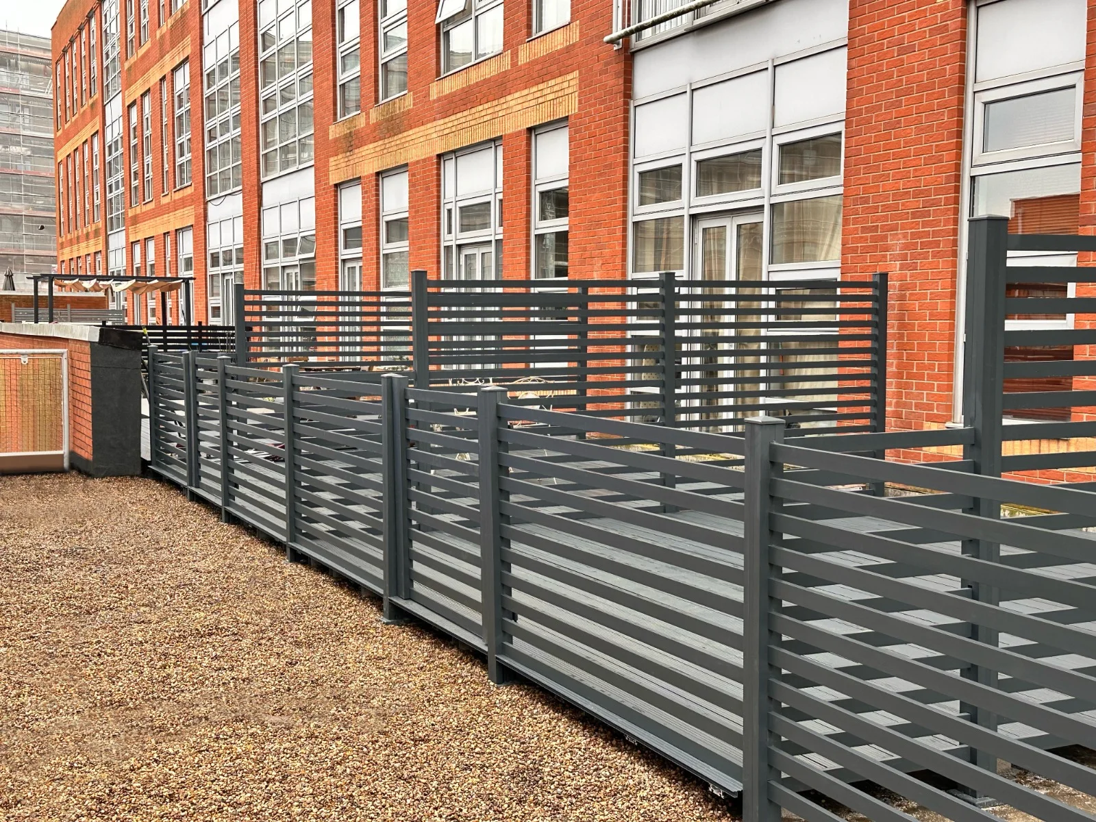 AluFence anthracite grey aluminium slat fencing along a gravel boundary