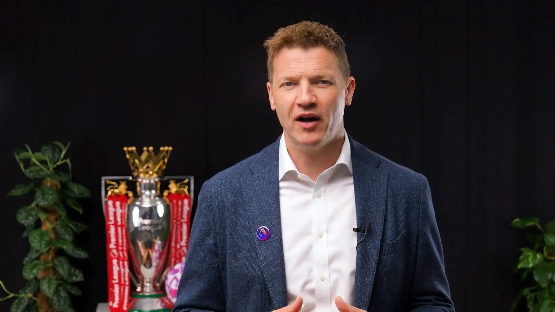A presenter delivering a Microsoft live update to camera in a studio setting.