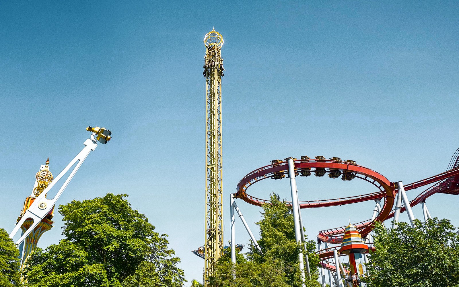 Hullámvasutak és vidámparki játékok a tiszta kék ég alatt a koppenhágai Tivoli Gardensben.