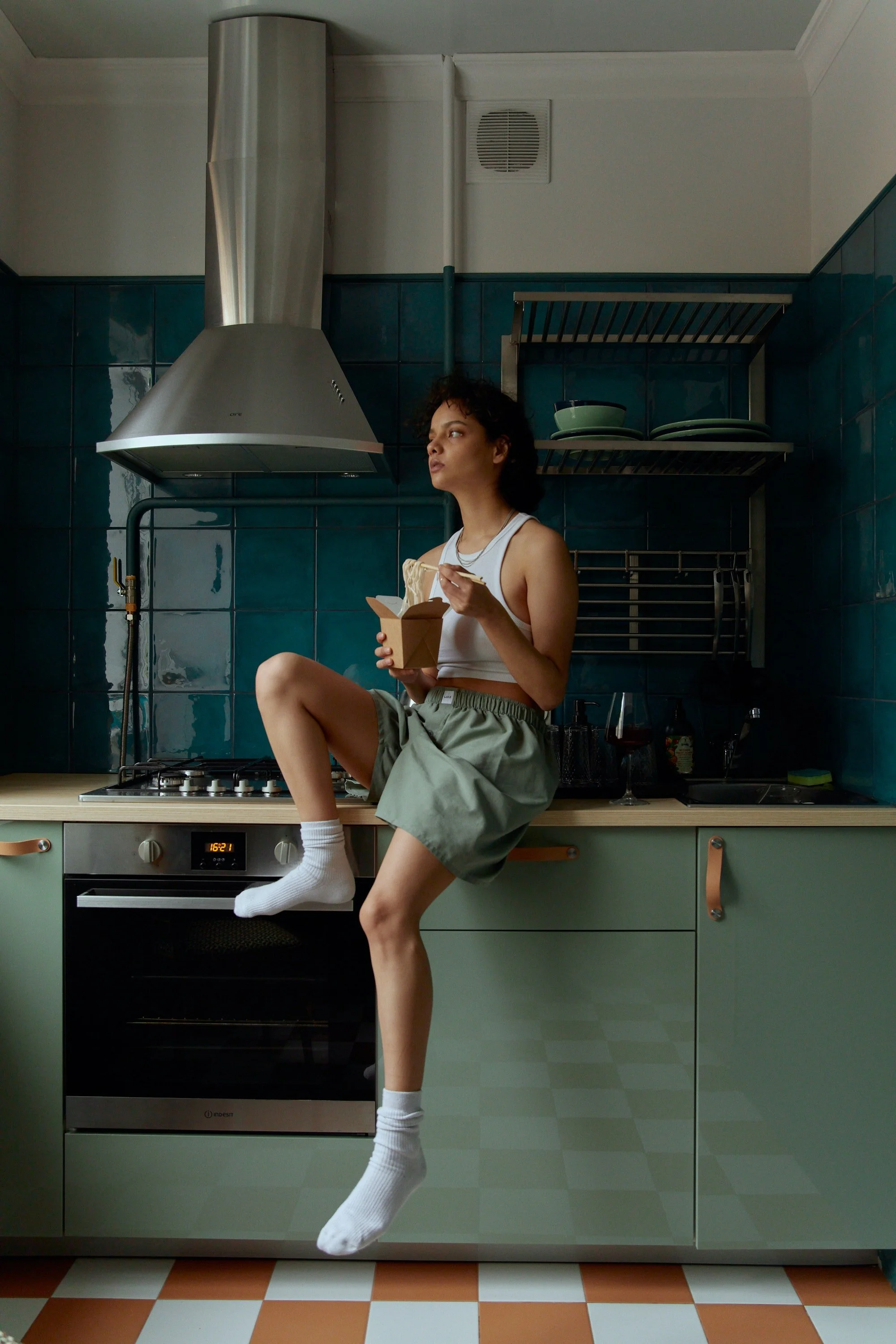 A woman sitting on her counter, eating a snack