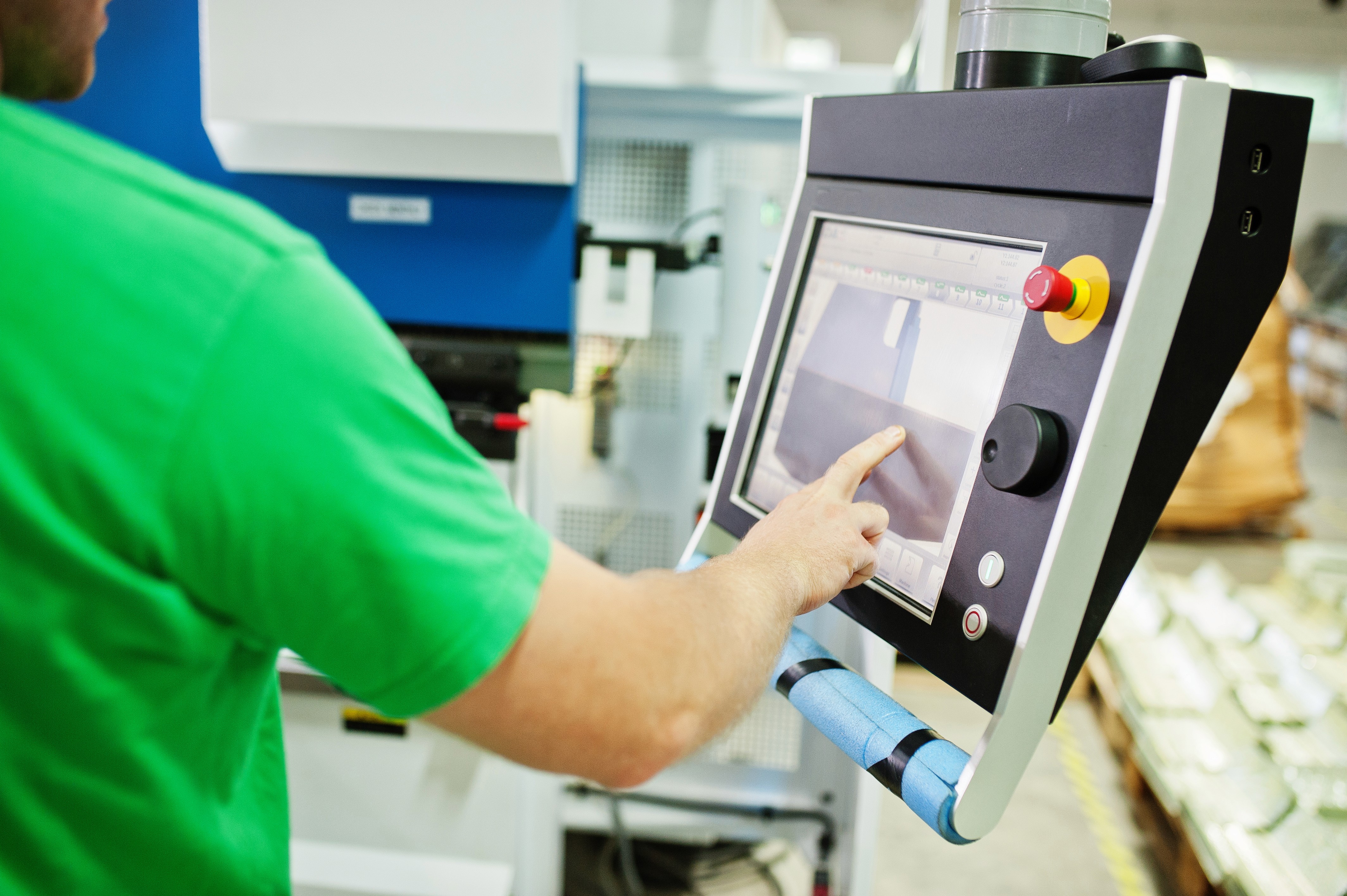 A packaging shop floor operator using a touchscreen interface on industrial machinery, representing the modern web platform Smart Data built to replace the legacy VB6 desktop application.