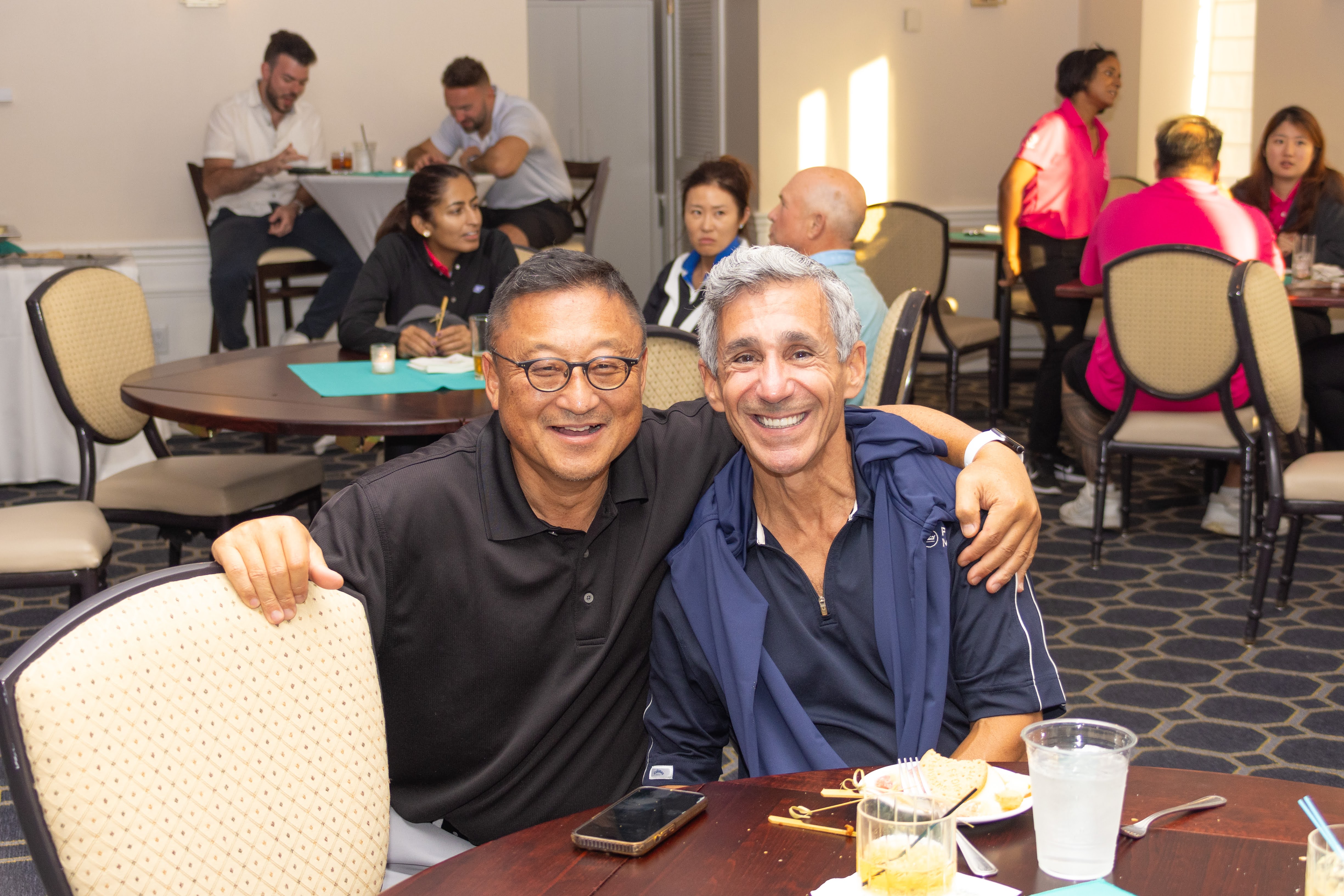 Two men pose for a photo at a dining table