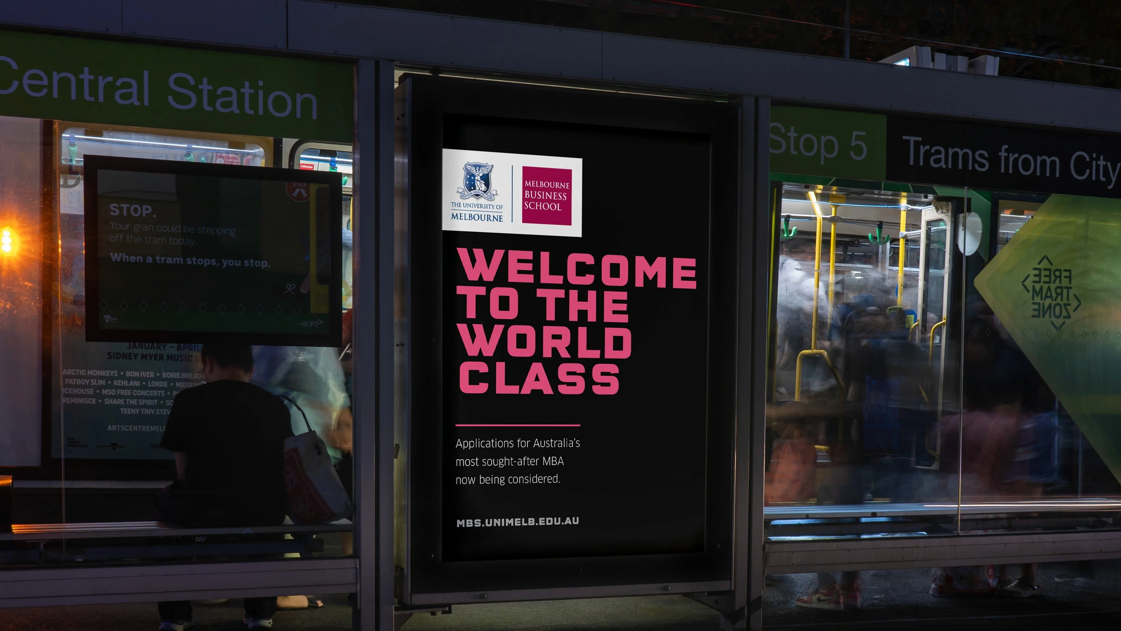 Melbourne Business School tram stop poster at night: 'Welcome to the world class', with MBA applications now being considered