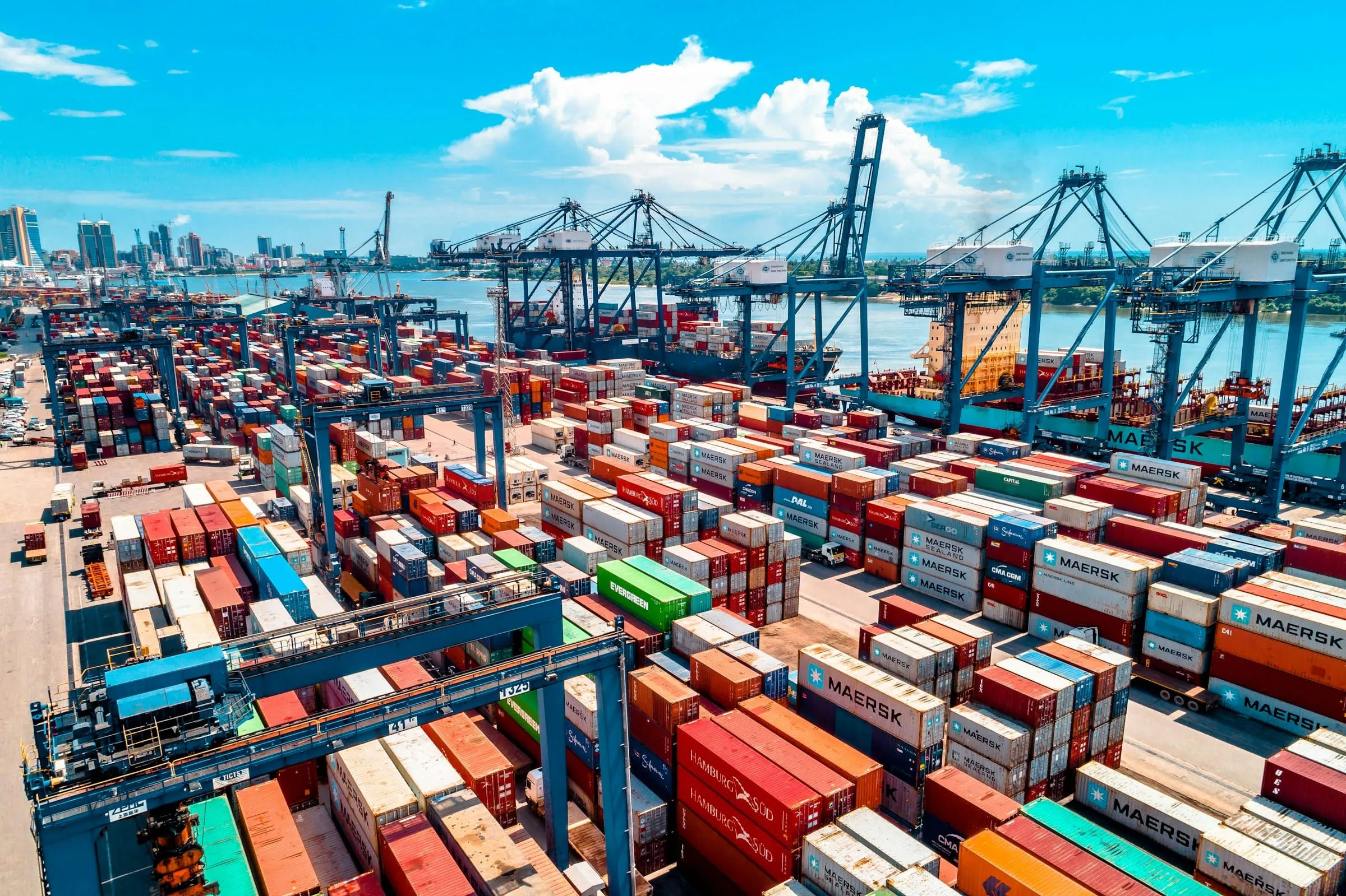 An aerial view of a busy container port, with stacked containers and ship-to-shore cranes
