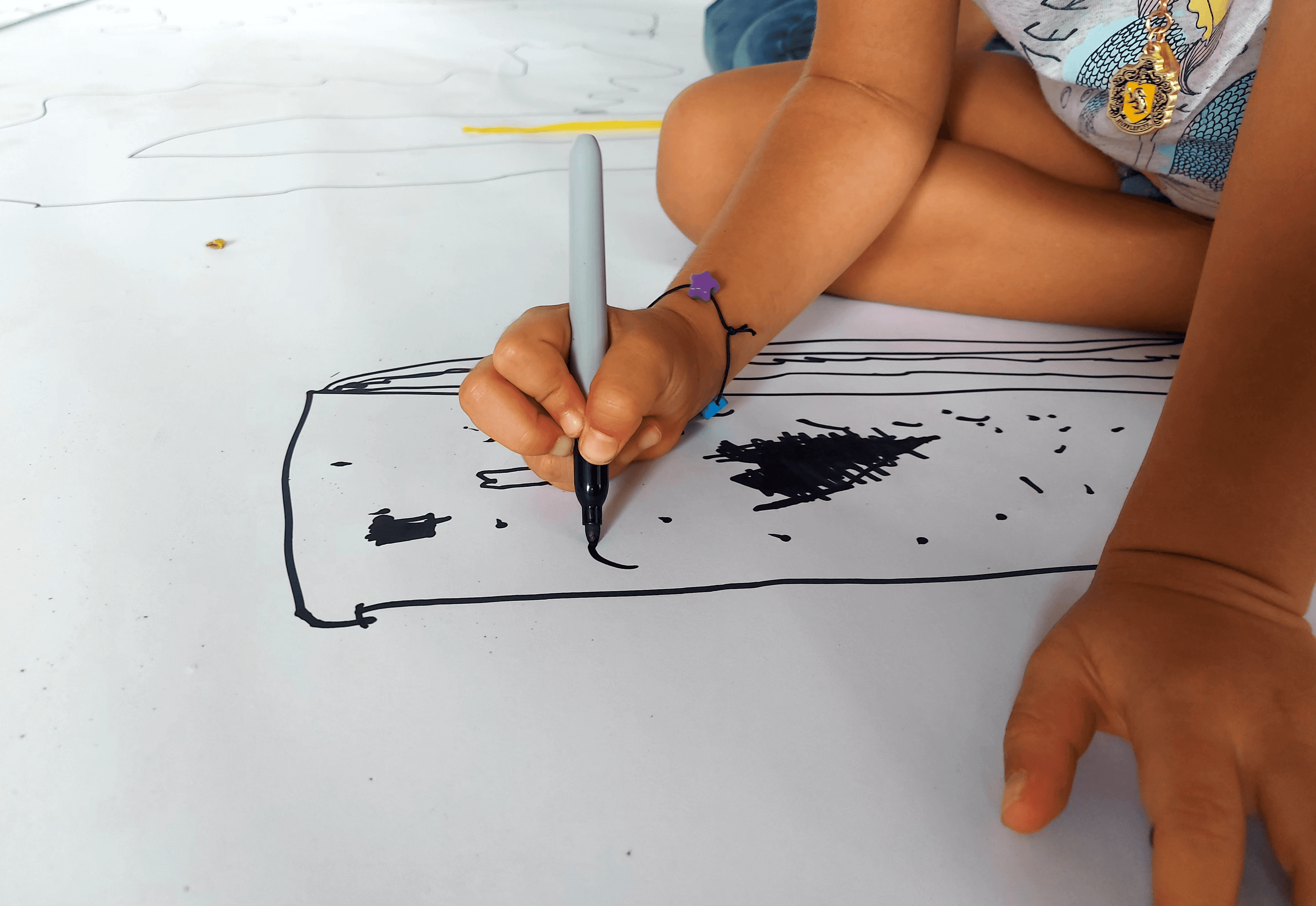 Niño concentrado dibujando con marcador negro, representando la creatividad infantil y el aprendizaje práctico