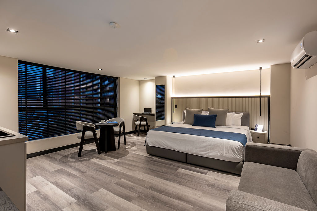 Habitación de lujo con cama king Medellín en Altus Hotel, con ventanales insonorizados y diseño elegante en Laureles.