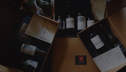 Gift boxes from Macchialina containing wine bottles, menus, and packaged items arranged neatly for presentation.