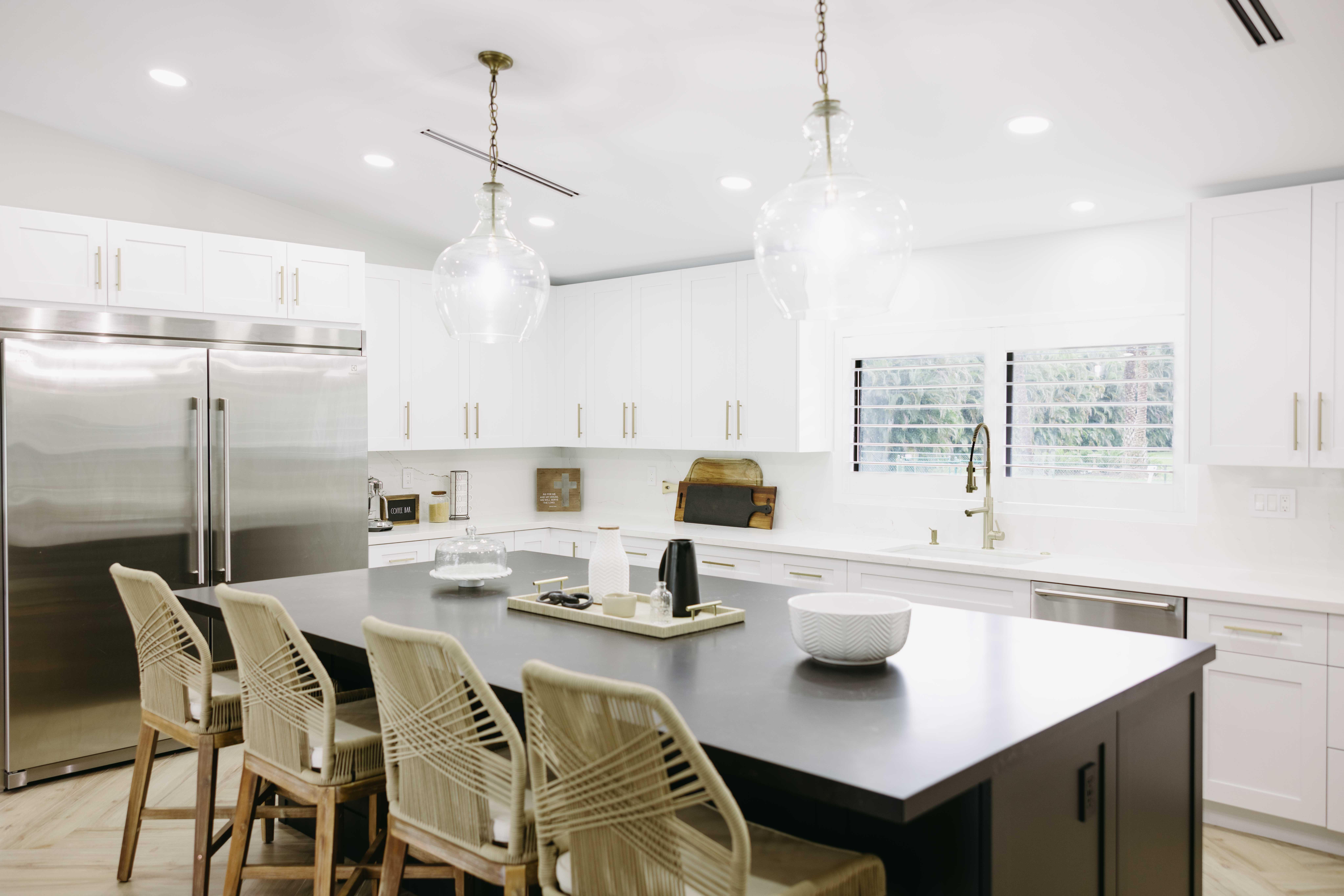 Modern kitchen with island, stainless steel appliances, white cabinets, and pendant lights.