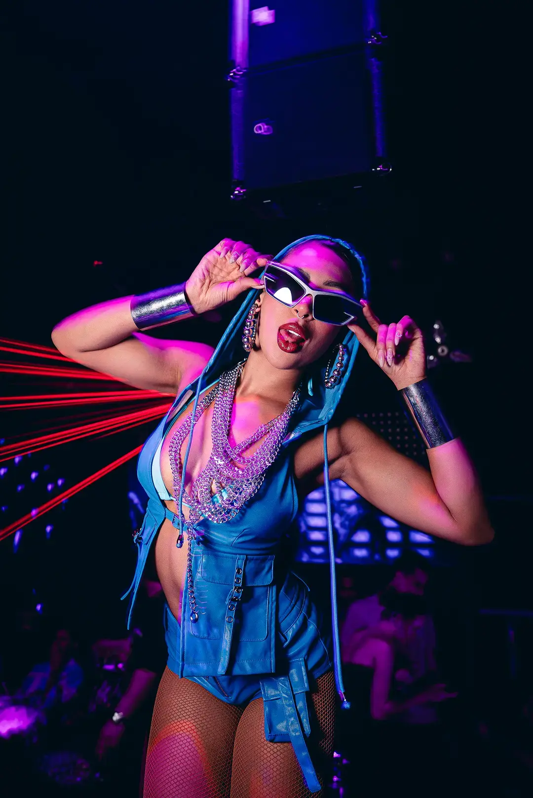 Performer in a blue hooded outfit with silver chains and sunglasses at The Myth Dubai