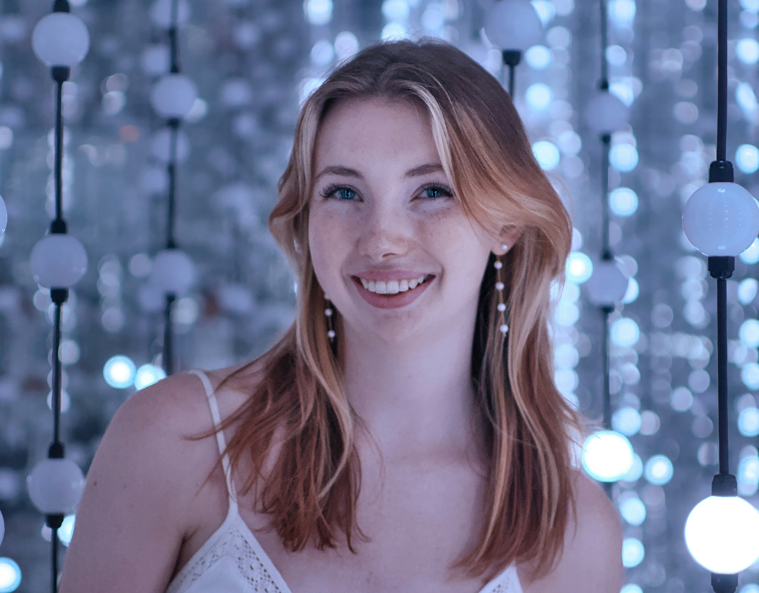Smiling woman poses in front of lights.