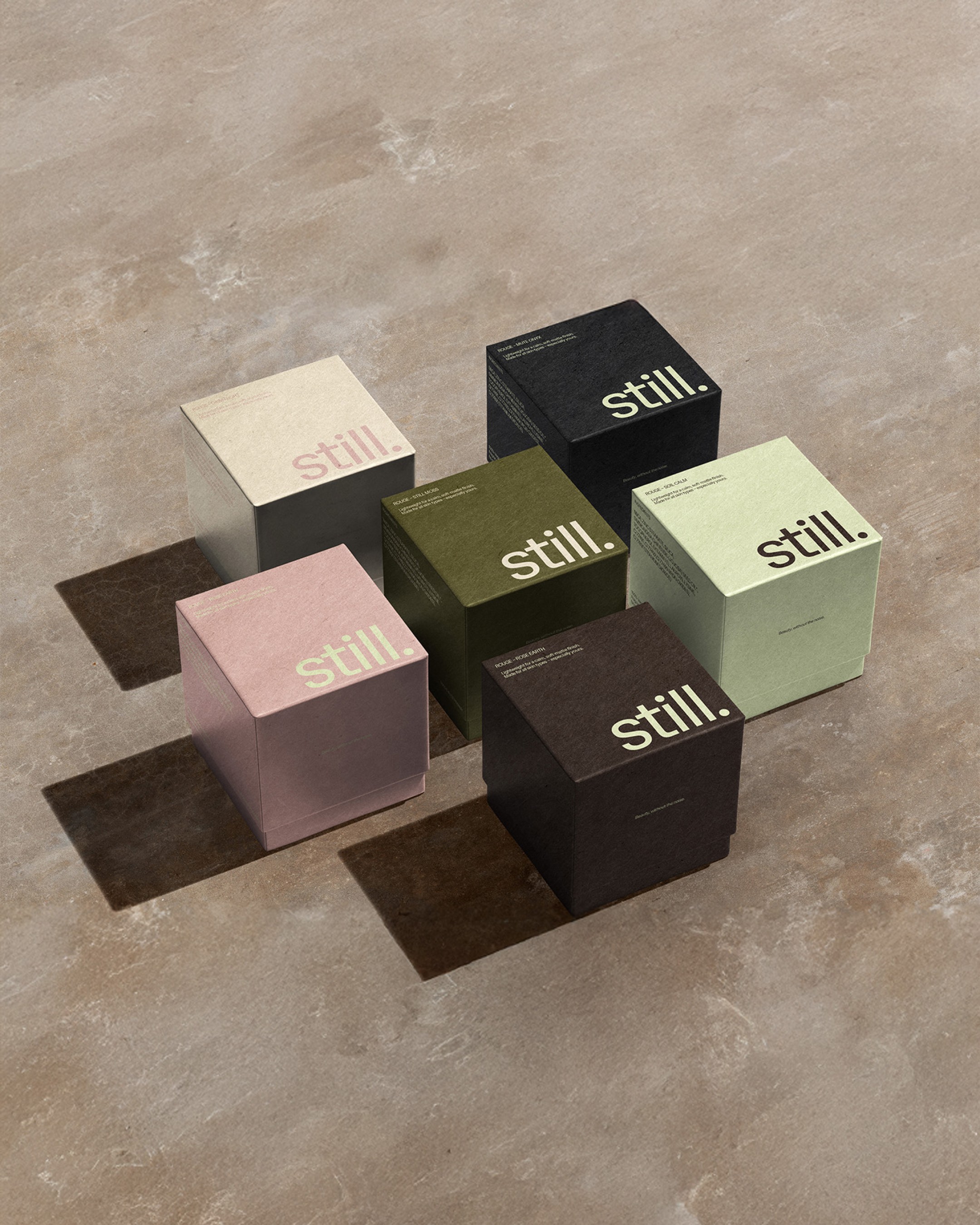 Five minimalist, colored boxes with the branding "still." are arranged on a neutral-toned surface, reflecting a modern approach to visual identity design, suitable for independent brands and creative entrepreneurs focusing on values-led branding.