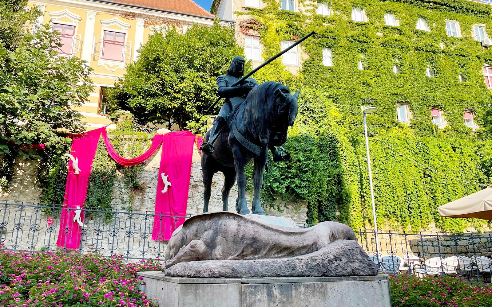 位於薩格勒布的騎士雕像，四周環繞著綠色植物和粉紅色裝飾。