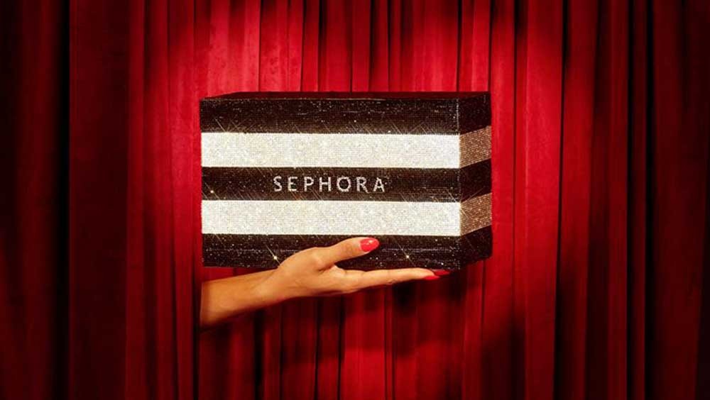Hand holding a striped Sephora shopping bag through red theater curtains