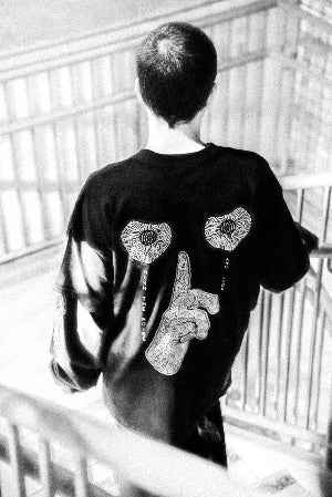 Person wearing a black t-shirt with decorative designs on the back, walking down stairs.