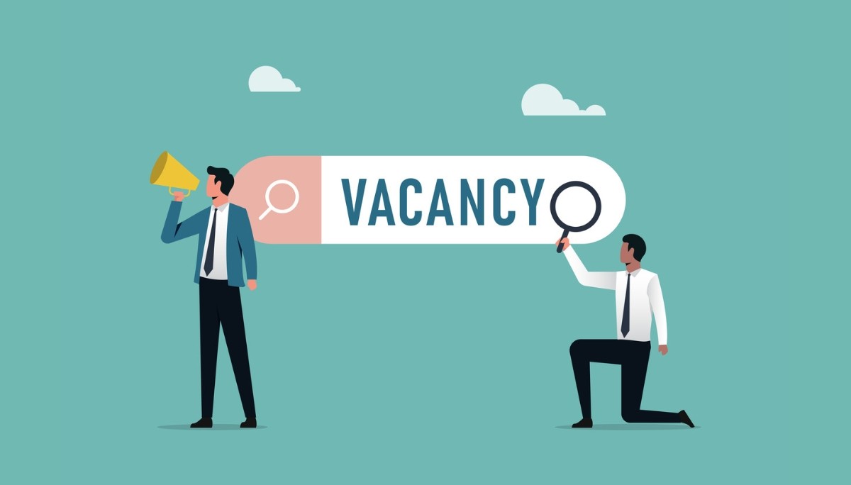 Illustration of professionals interacting with a large search bar labeled “VACANCY,” using a megaphone and magnifying glass.