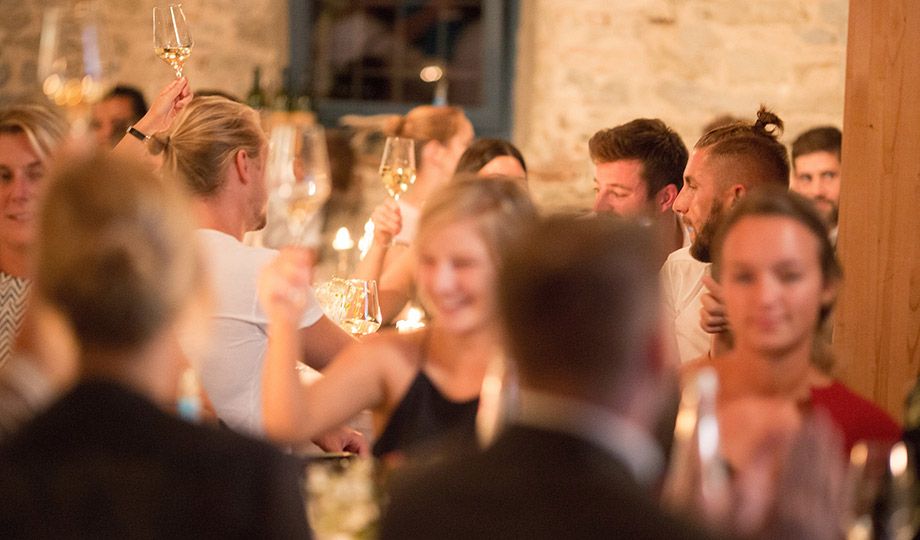 Glückliche Hochzeitsgäste beim Anstoßen im festlich geschmückten Innenbereich der Villa Sommerach.