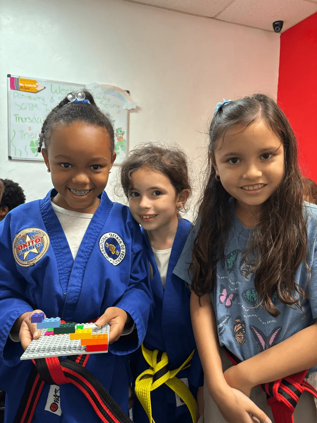 A uniformed educator demonstrates a hands-on aquatic learning activity with toy fish in a blue water tray to a diverse group of engaged elementary school students in a colorful classroom.