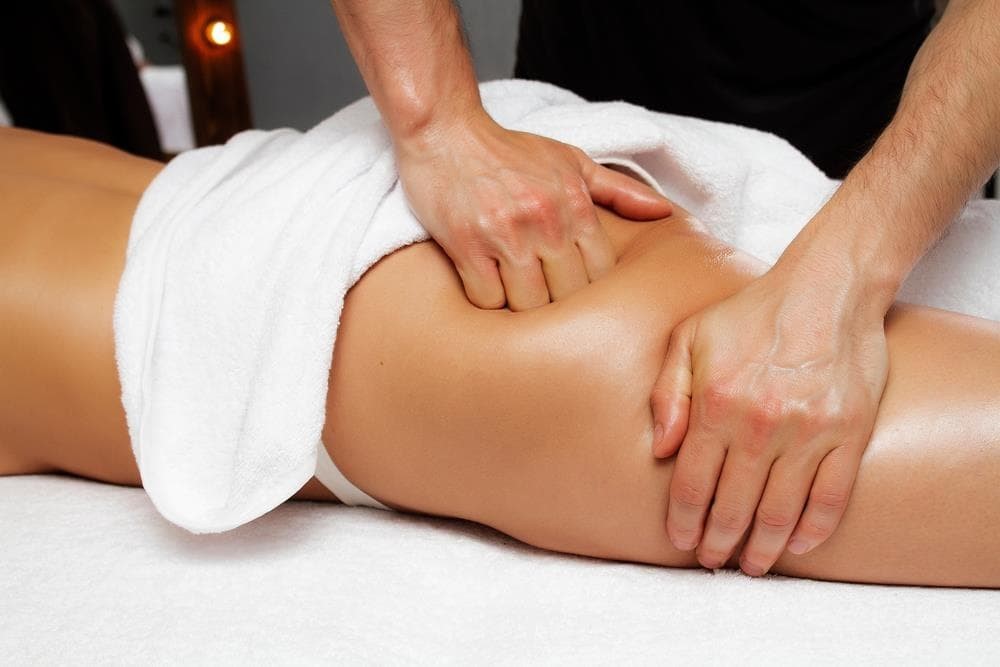A woman lying down with a towel wrapped around her head, her face glowing with facial oil. She has a peaceful expression, enjoying a skincare treatment.