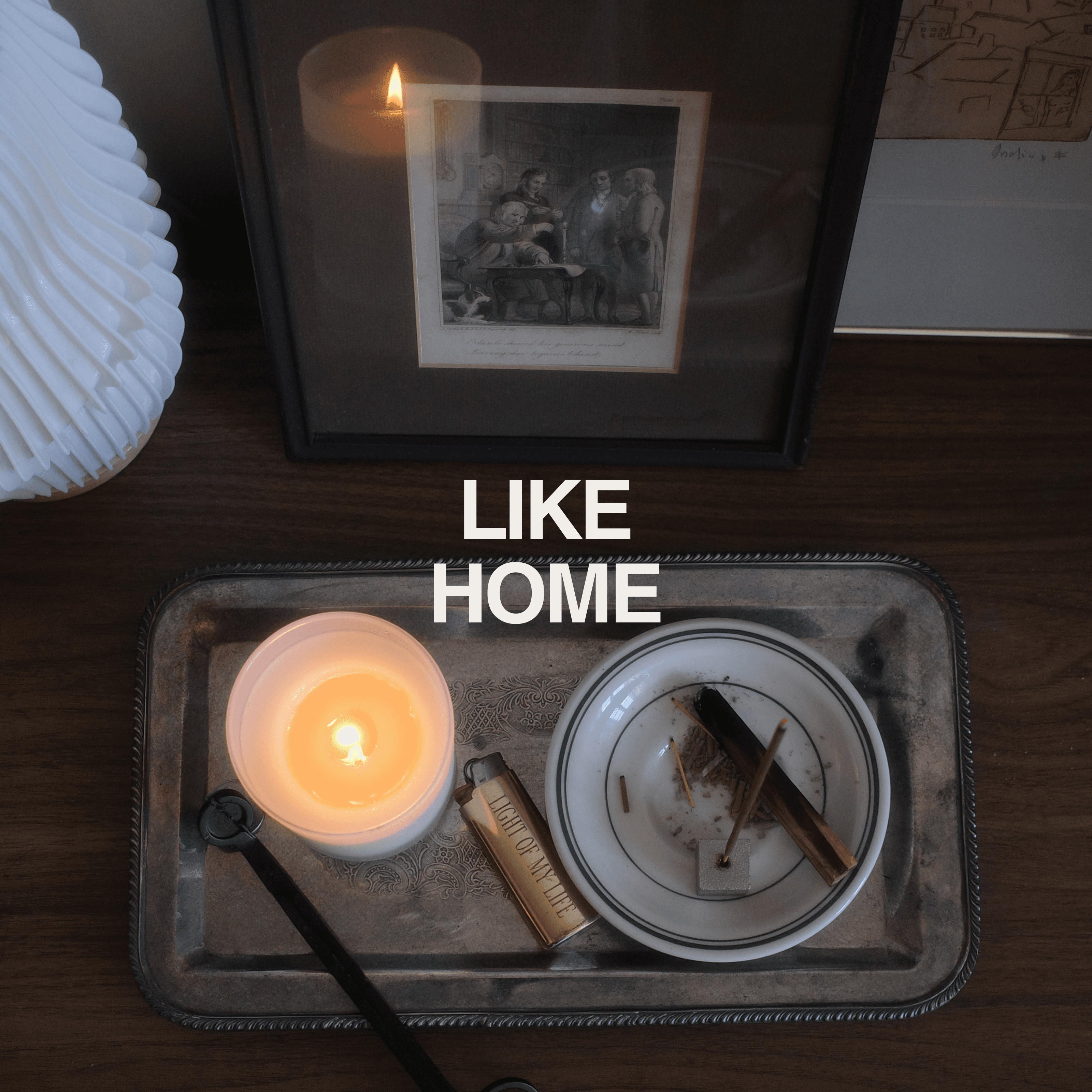 Cozy tray with candle, framed art, and matches on dark wood table, evoking everyday comfort and homey ambiance—Normy Home Playlist cover.