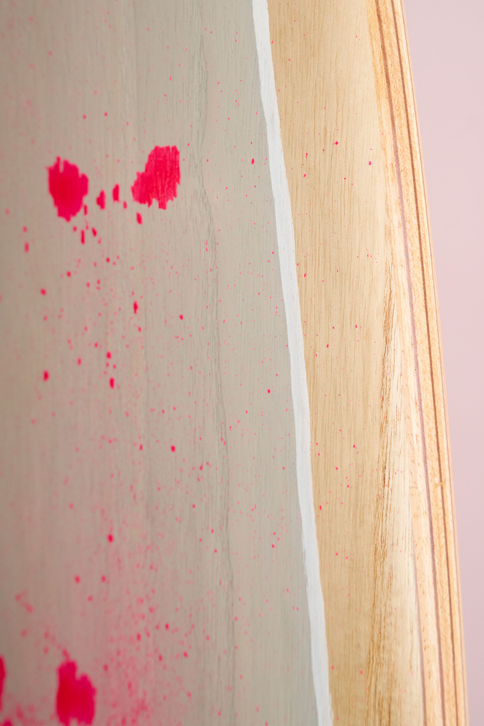 Grey and pink paint on a wooden surfboard