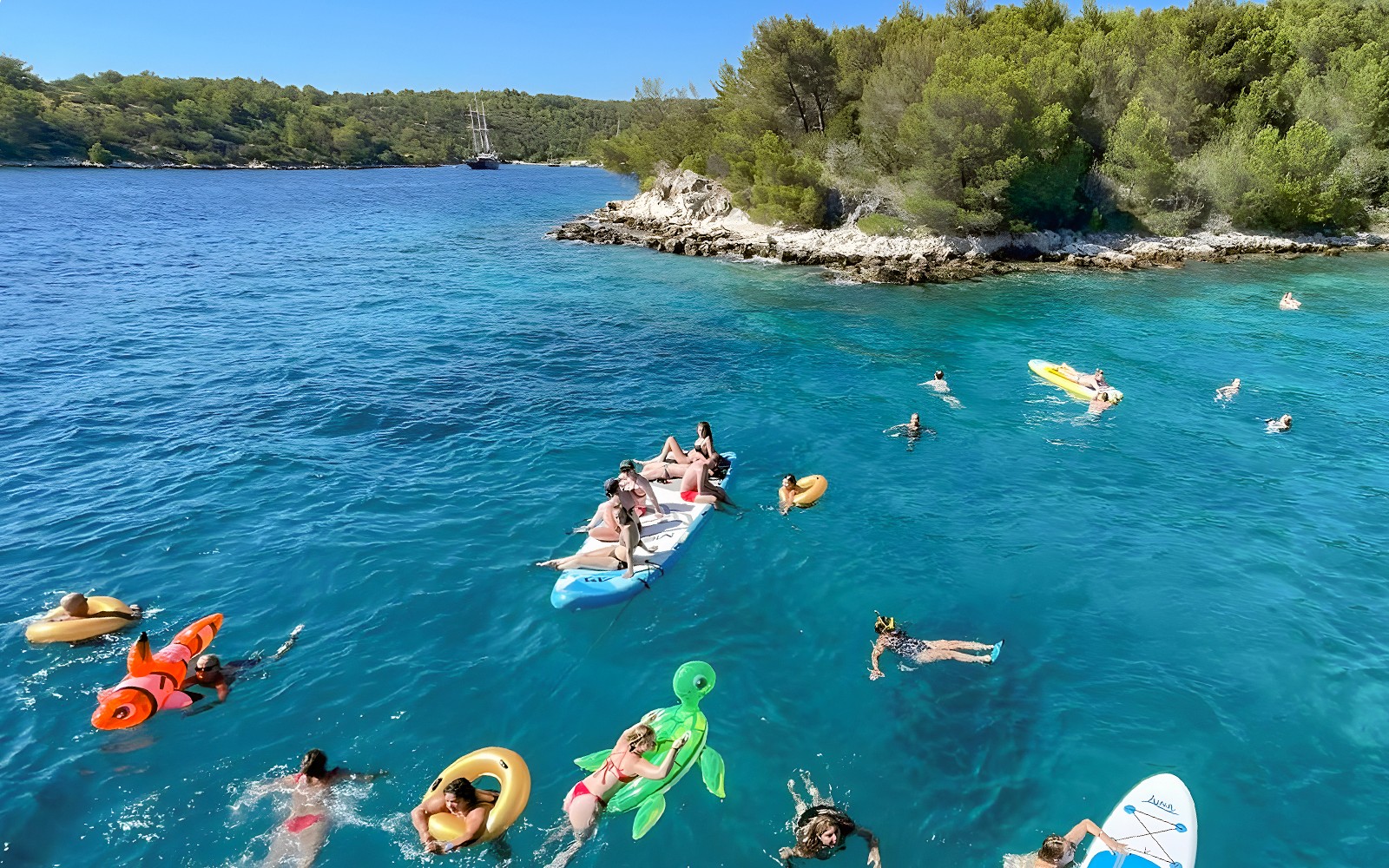 People enjoying a swim and paddleboarding near Hvar during a Split islands cruise.