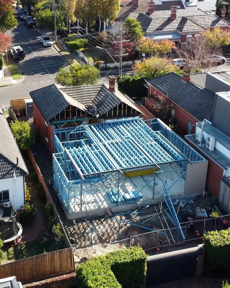 Residential house extension construction with steel framing in suburban neighborhood.