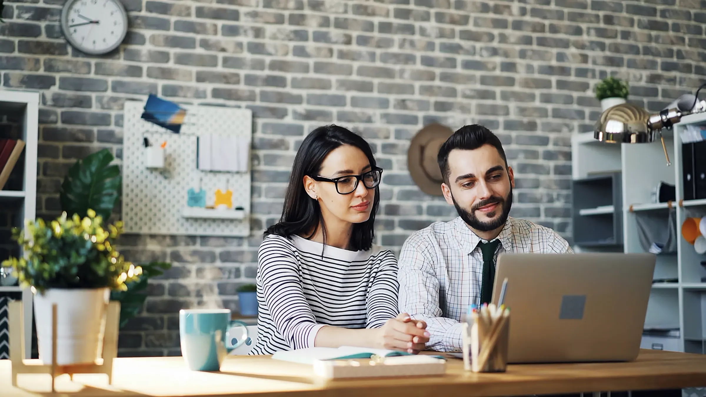 a man and a woman are sitting in front of their laptops.